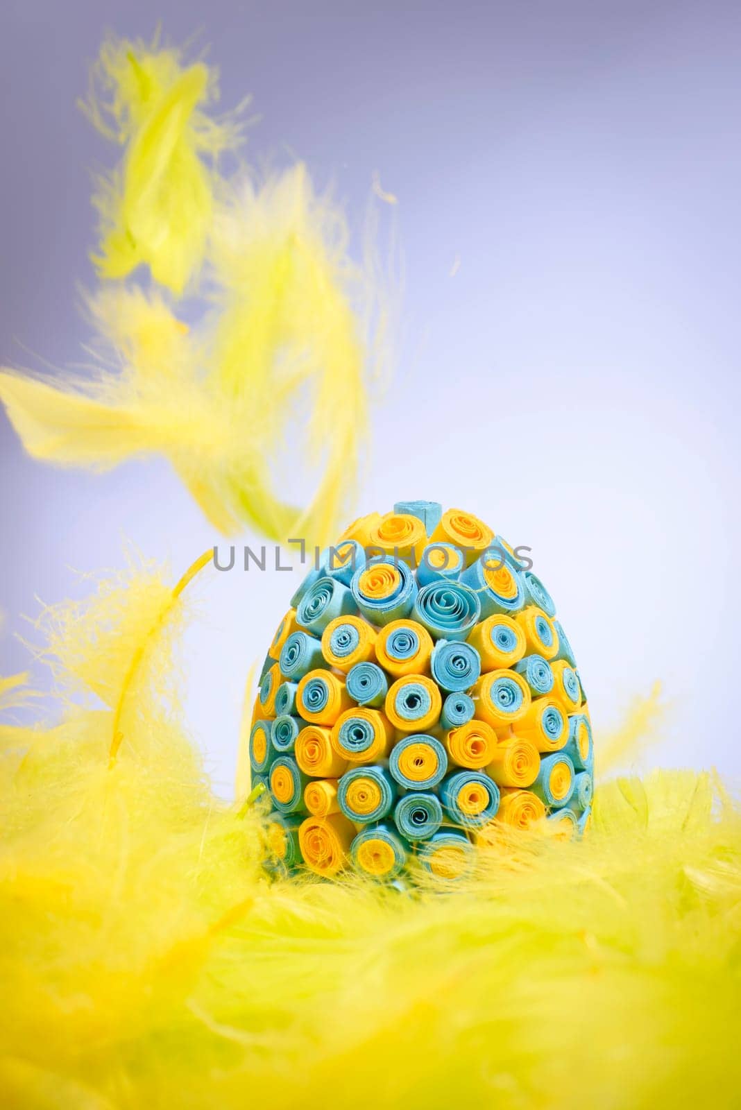 funny,amusing and joyful photo of yellow and black easter egg in yellow feathers,visible feather falling down.