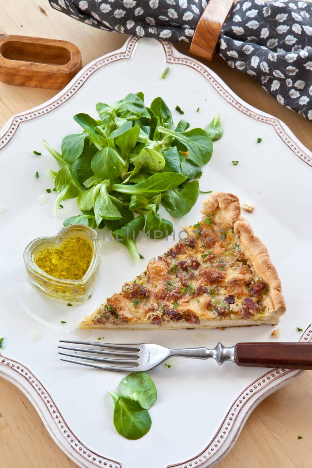 Square plate with quiche Lorraine and lamb's lettuce