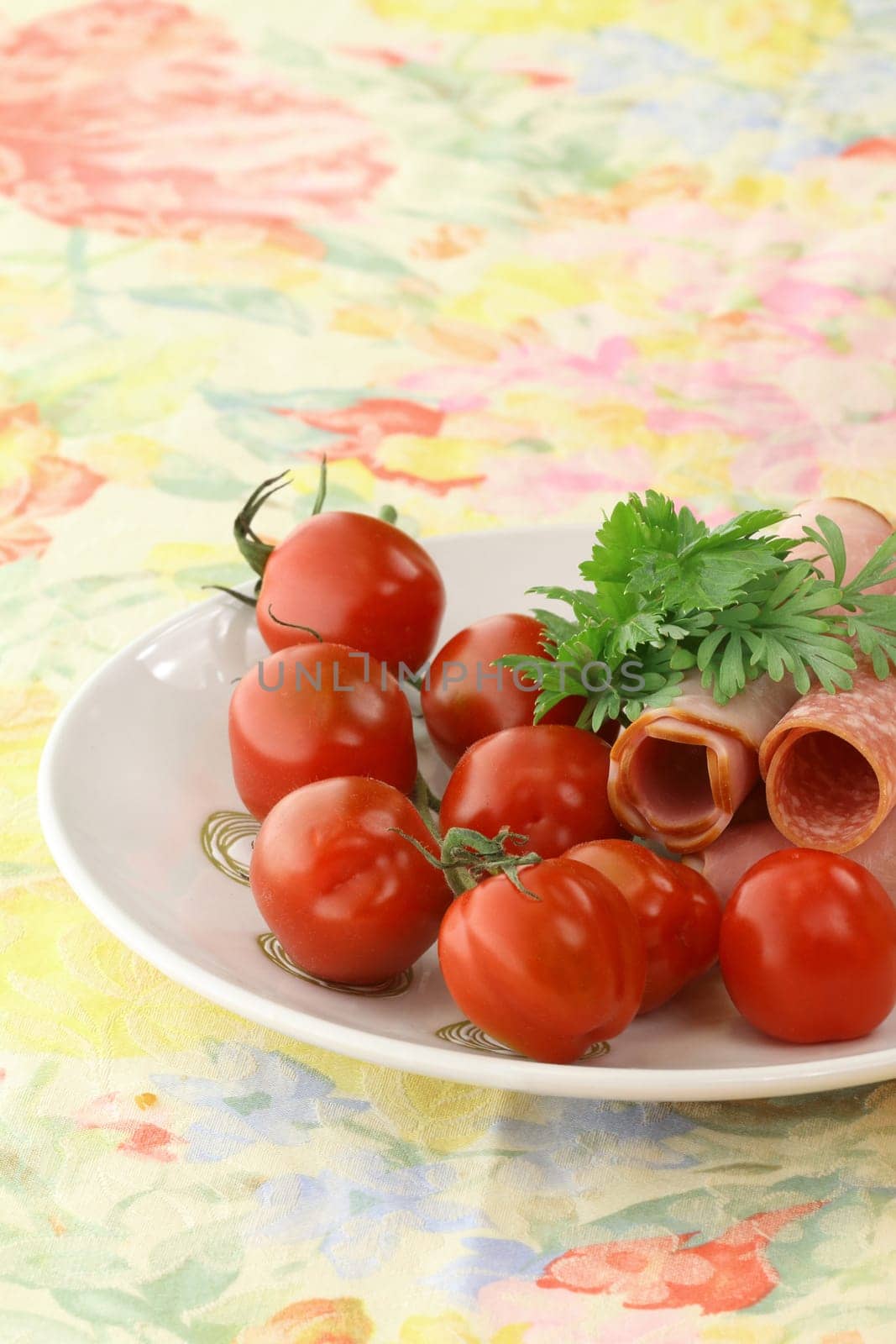 Detail of a breakfast table with tomatoes and cold cuts,arranged on a plate