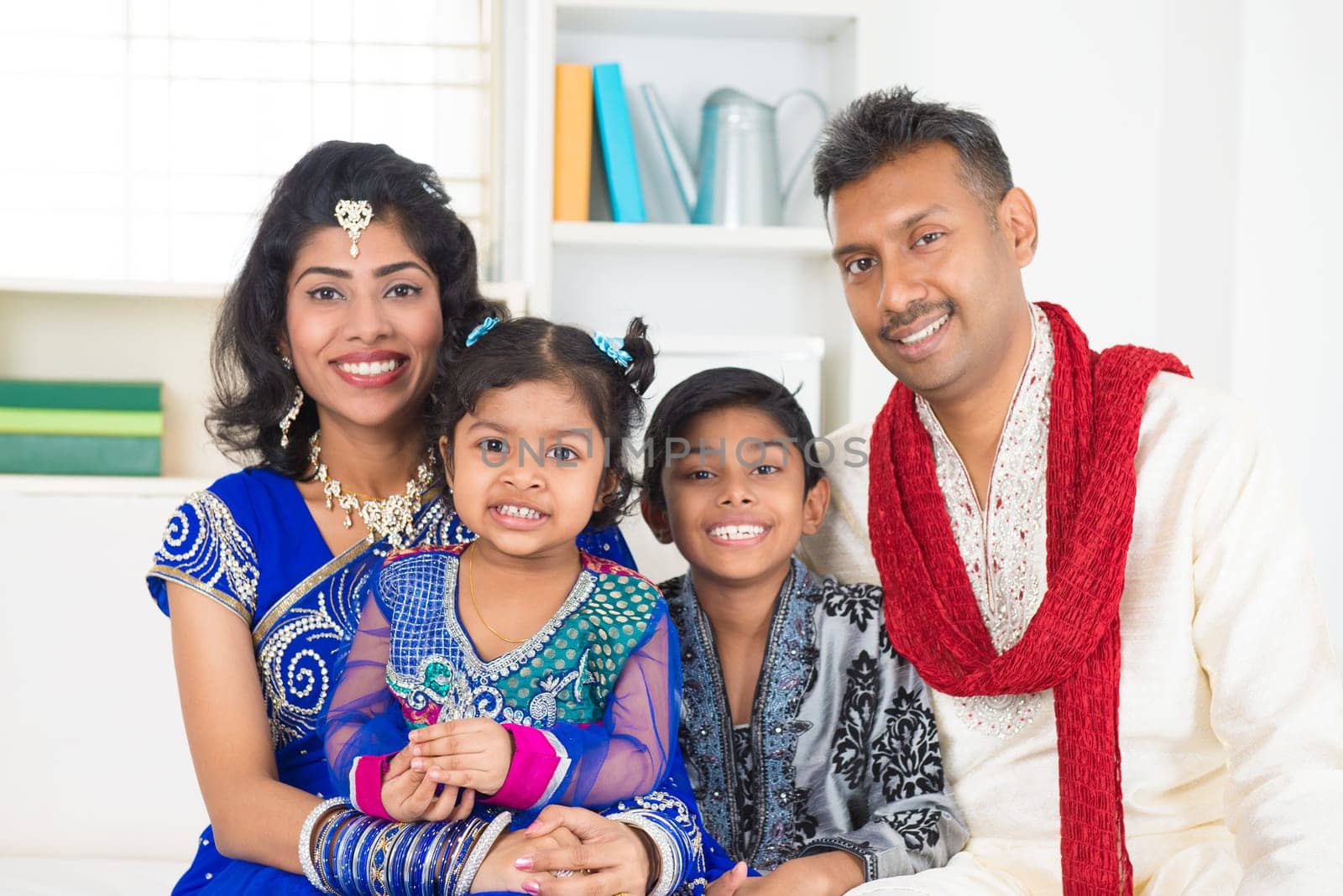 Happy Indian family at home. Living lifestyle of parents and children in their traditional dress in modern house.