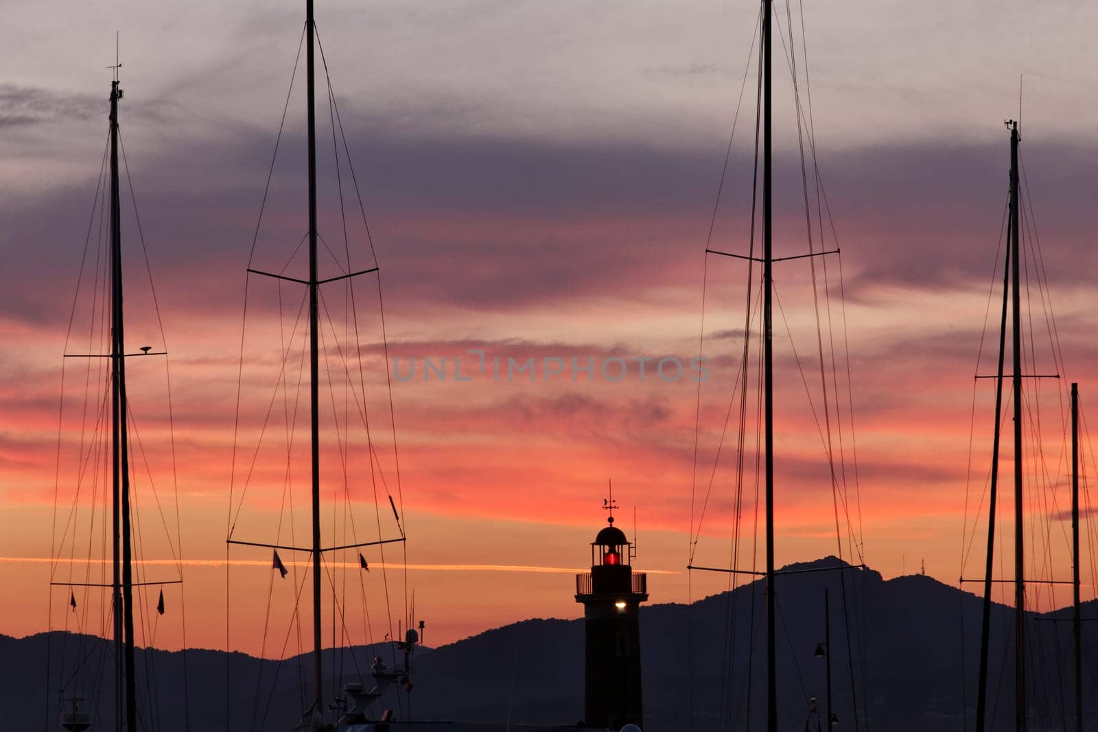 Saint-Tropez,sailing masts with lighthouse in the evening light,Cote d'Azur,Provence,South of France - Saint-Tropez,sailing masts with lighthouse in the sunset light,Cote d'Azur,Provence,Southern France