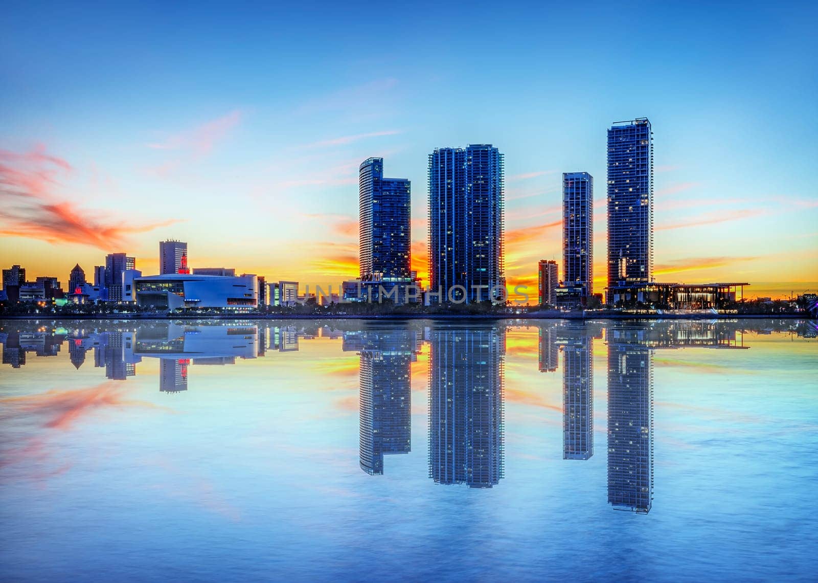 Miami city skyline panorama at dusk with urban skyscrapers over sea with reflection