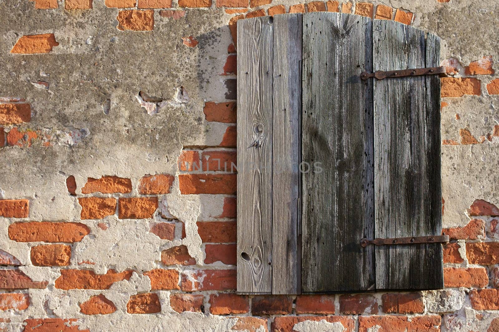 The close-up of a wooden hatch in the brick wall of a barn.