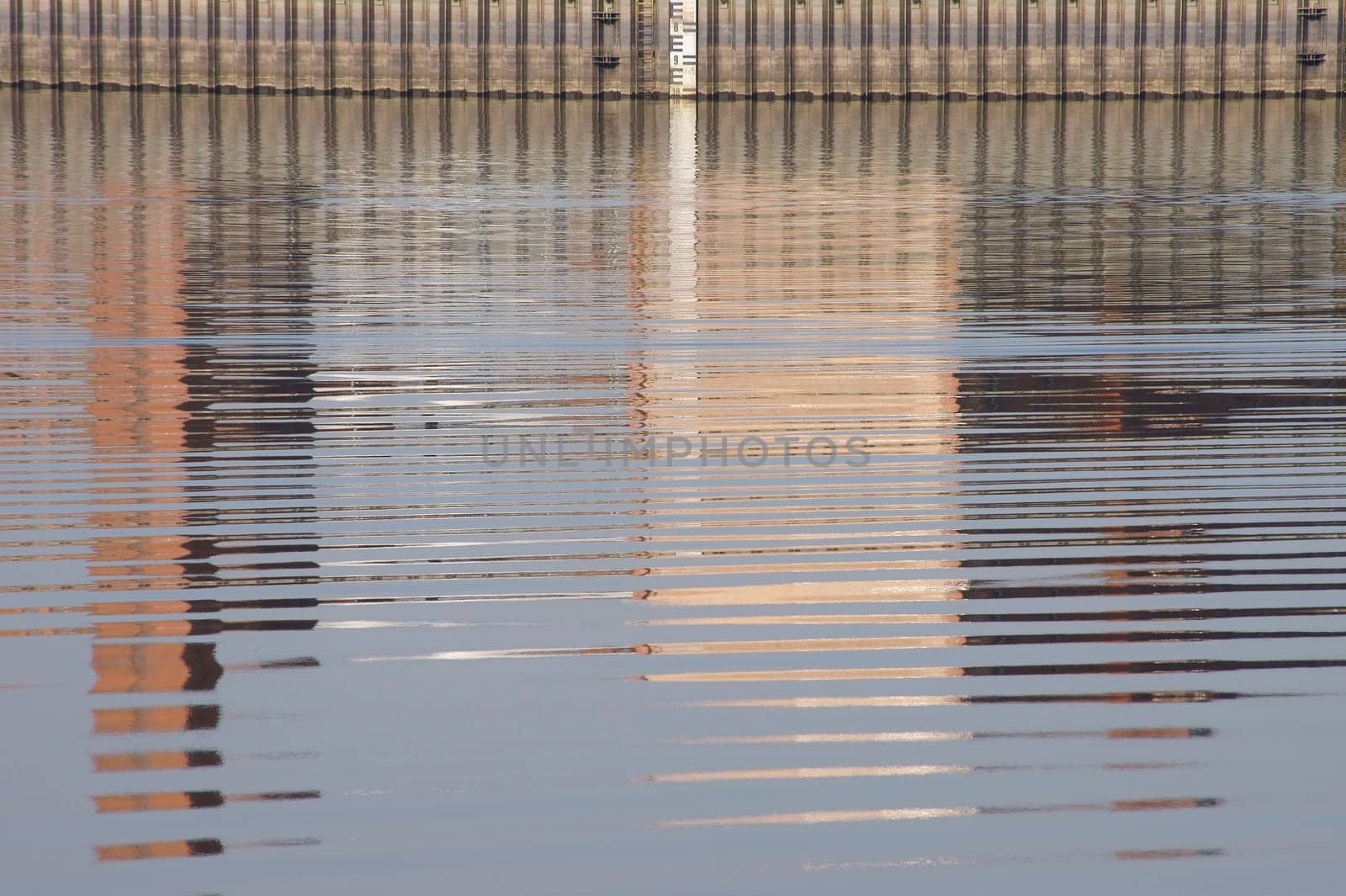 The photograph of water reflections on a dam wall.