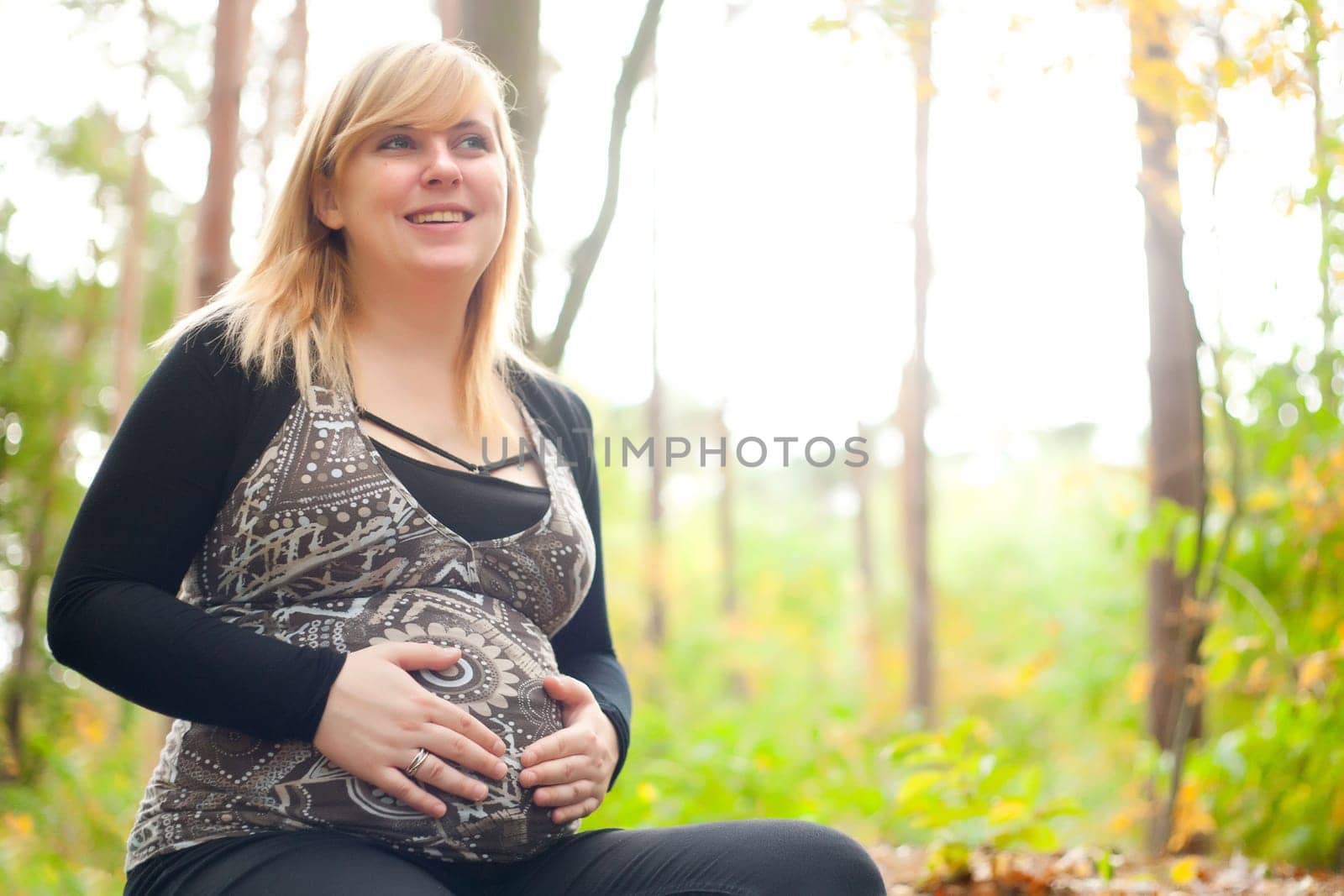 Blond young girl is waiting for her little child. Shoot in the forest