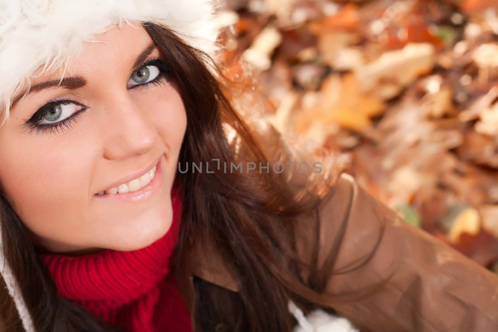 Happy brunette is having a nice time in the park while it's autumn