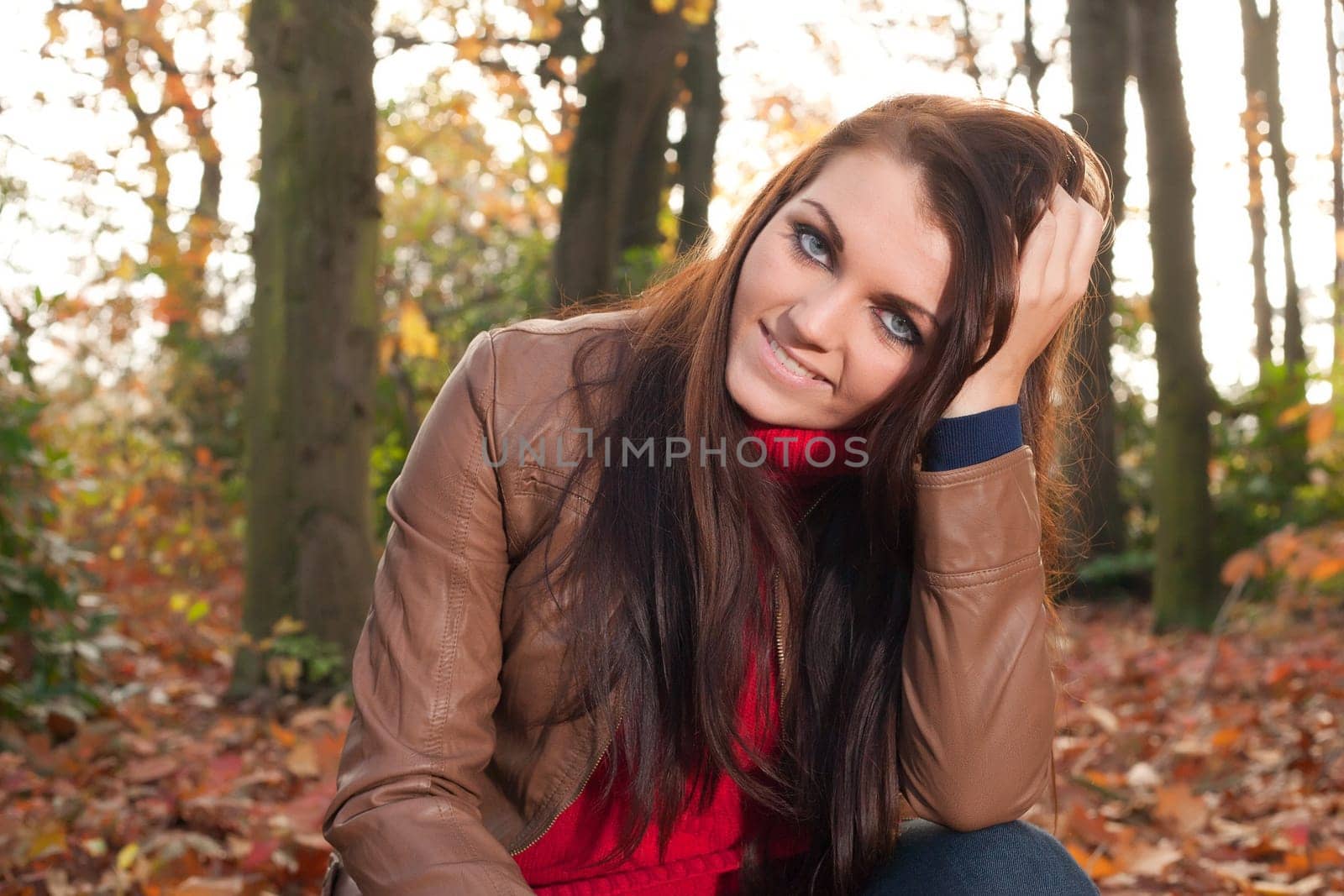Happy brunette is having a nice time in the park while it's autumn
