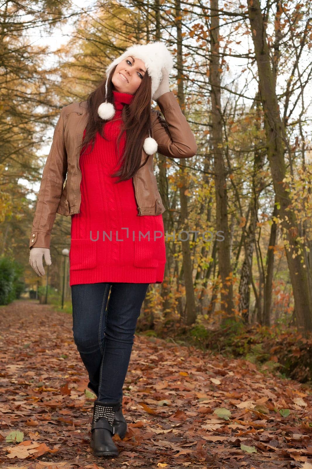 Happy brunette is having a nice time in the park while it's autumn