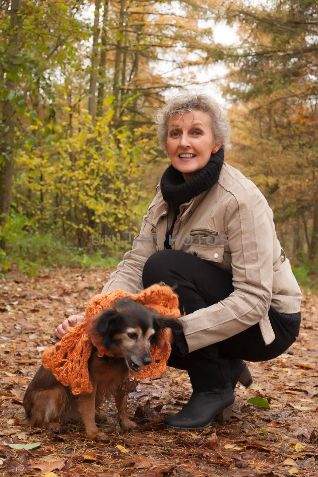 Middle aged woman in the autumn forest with her dog
