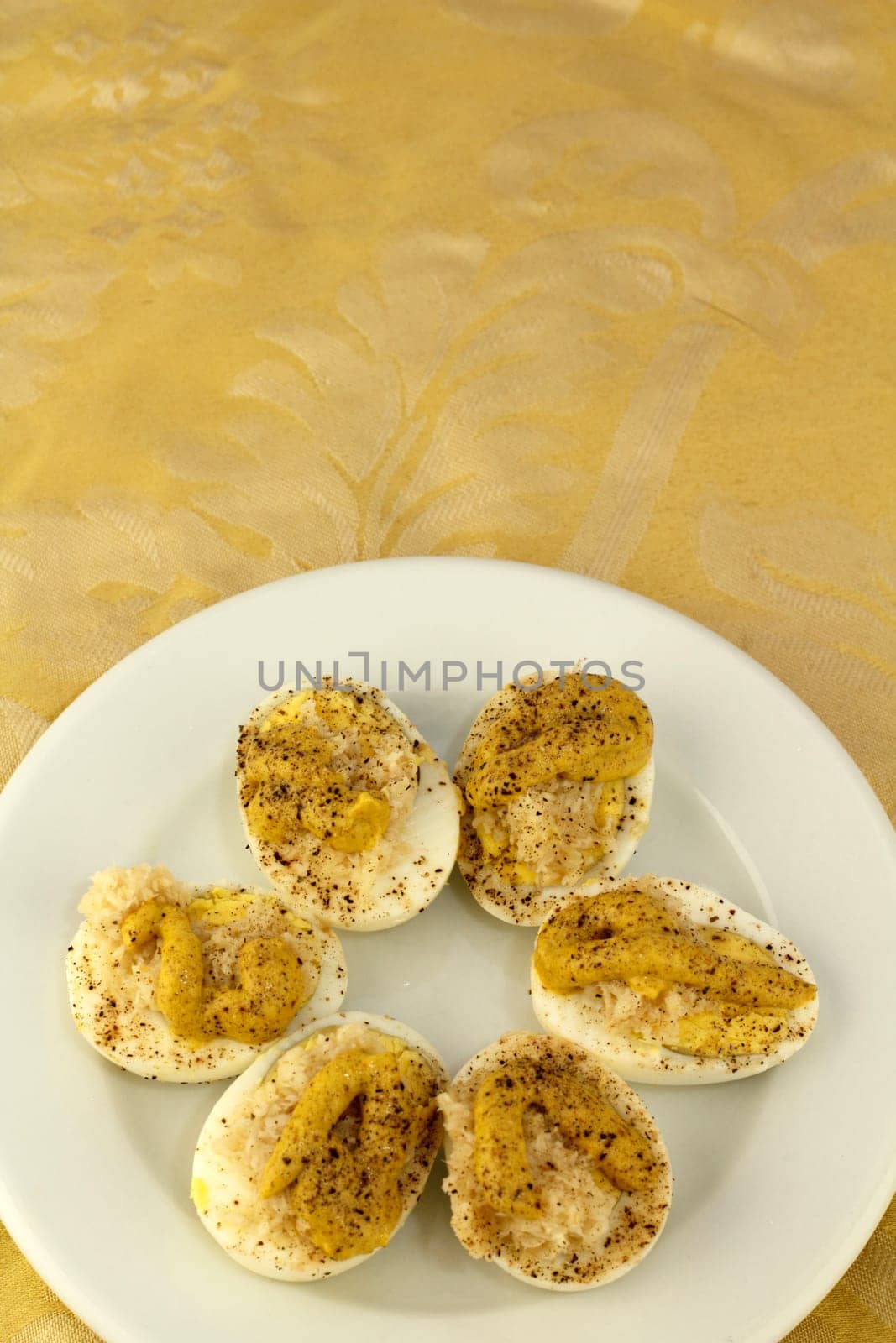 A small white plate full of prepared deviled eggs appetizer with horseradish, mustard, mayonnaise, salt and pepper.