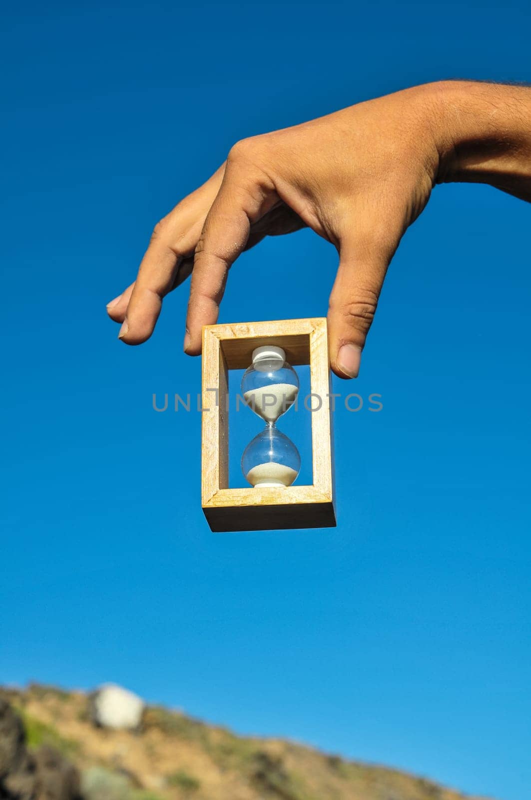 Time Concept White Sand Hourglass on the Volcanic Rocks