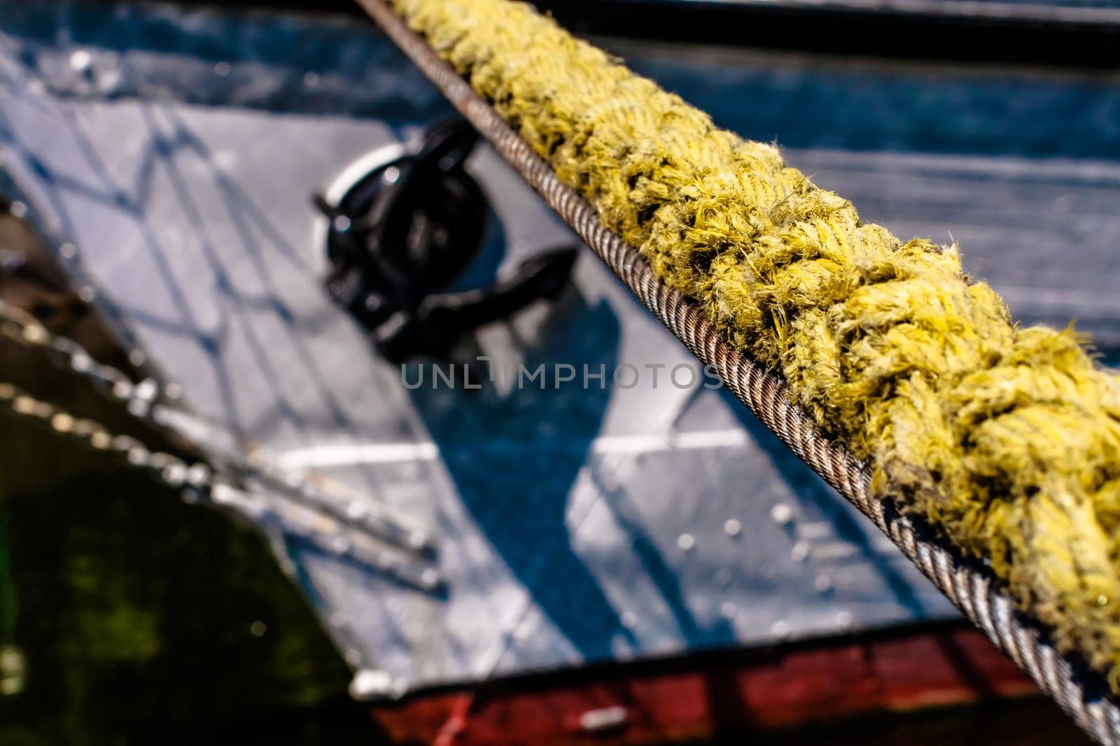 thick yellow hawser,mooring line with blurred visible piece of the ship,anchor visible.