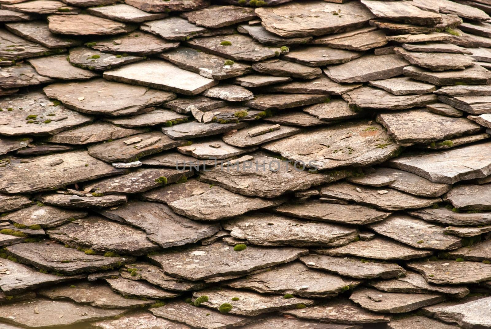 Stone tiles of slate-roof rural house as background