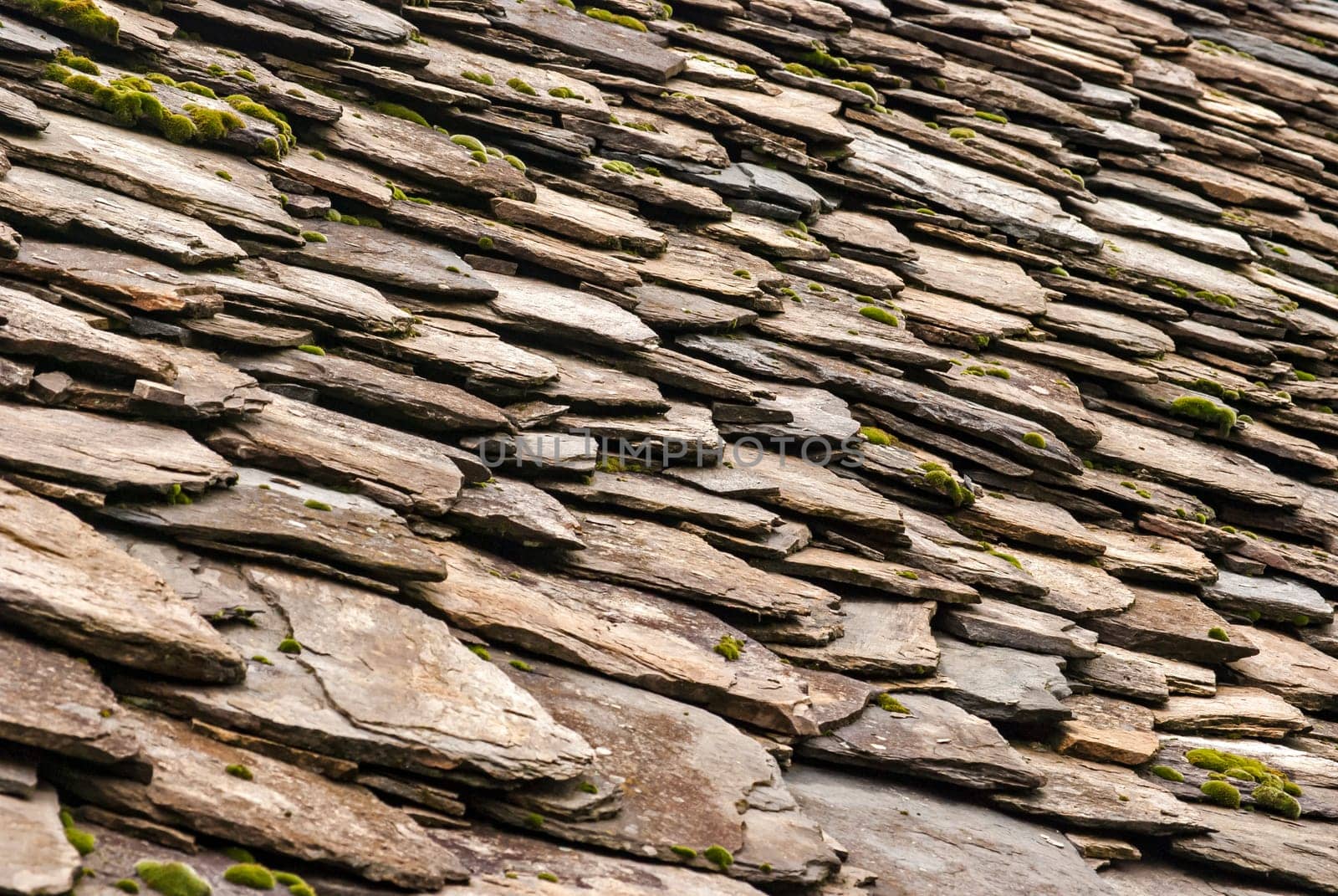 Stone tiles of slate-roof rural house as background