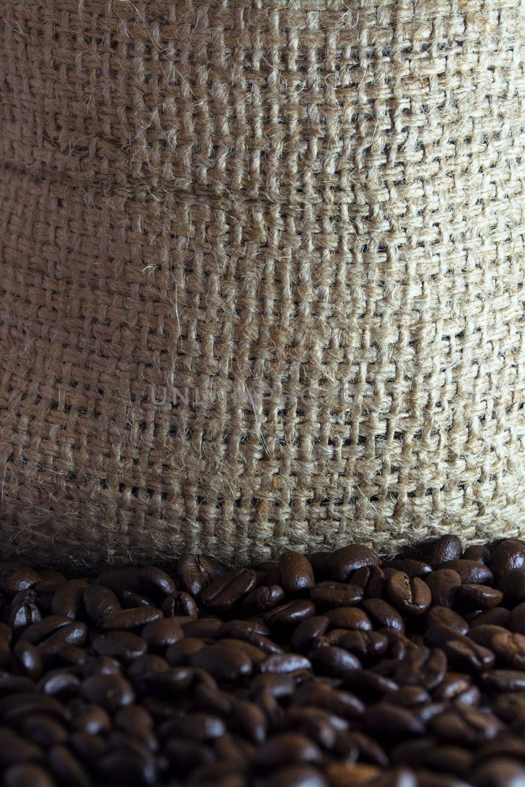 Coffee beans in a small clay pot. Image has a background of jute fibers