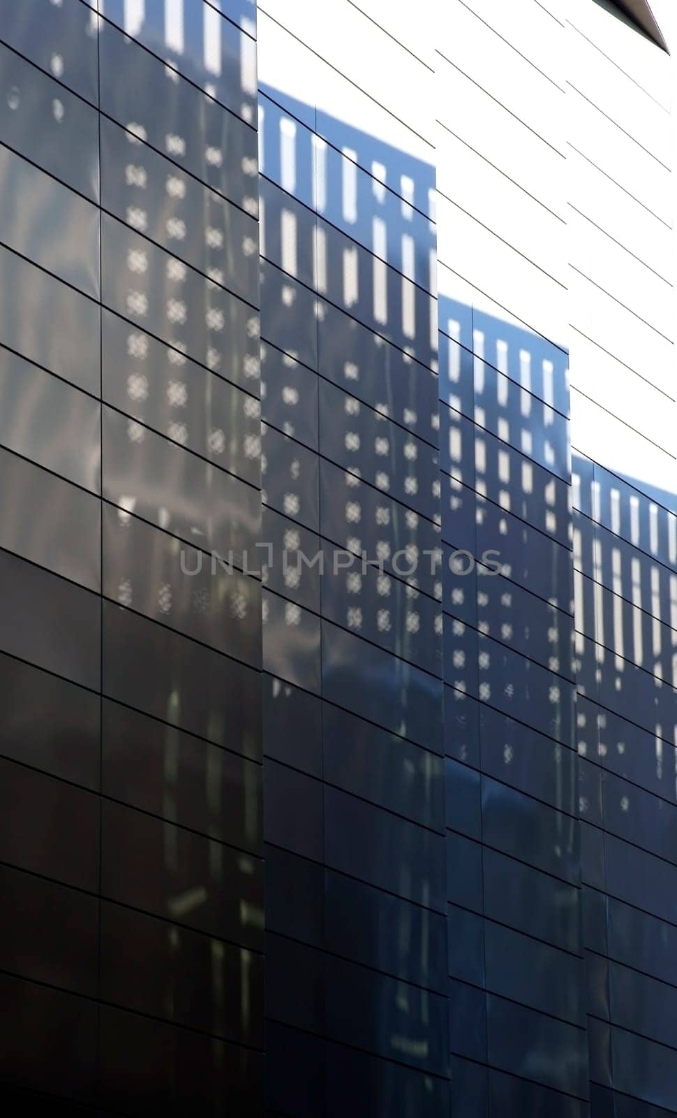The photography of light reflections and shadow patterns on a striking sheet metal facade.