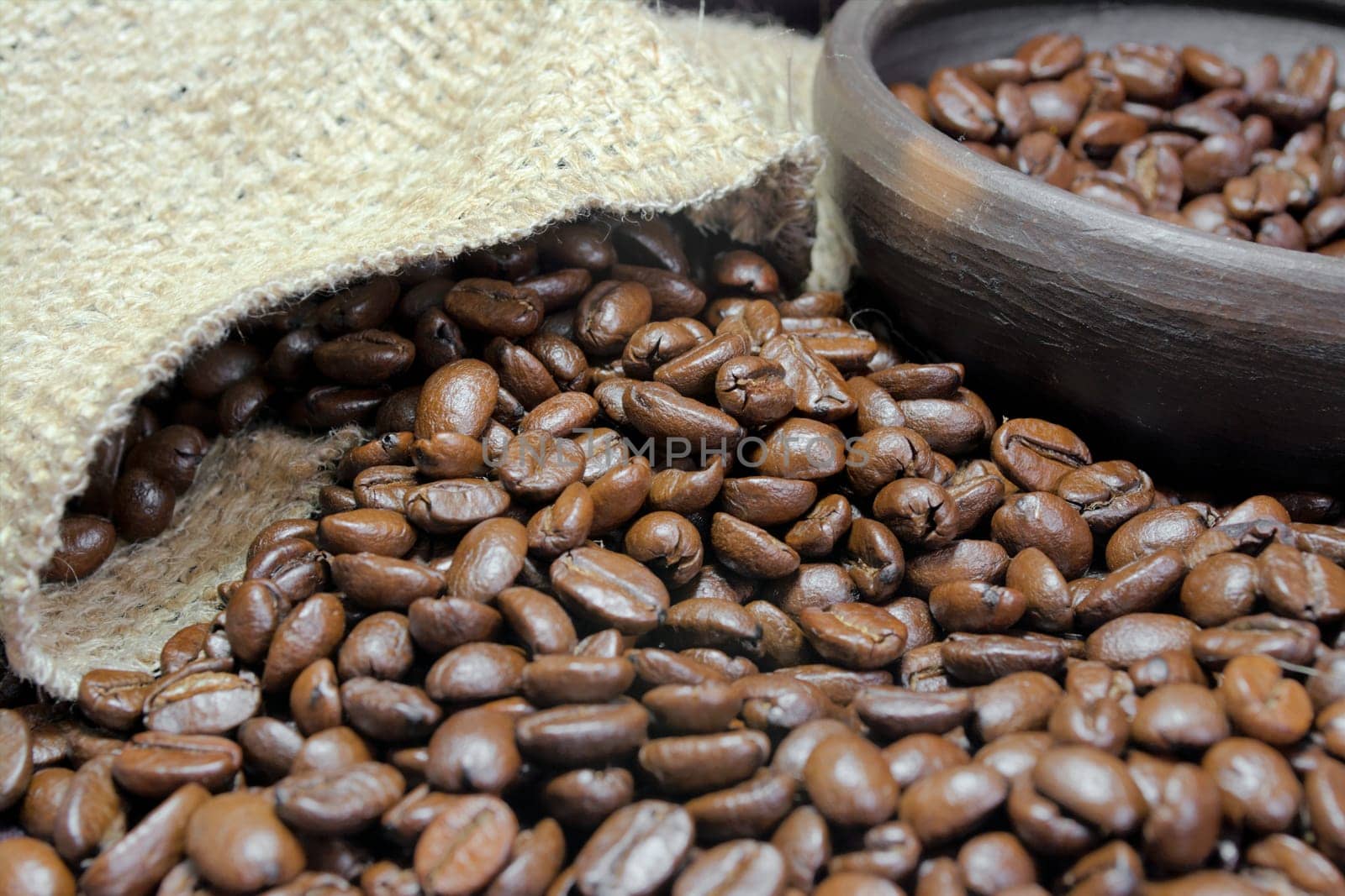 Detail of coffee beans, small clay pot and jute bag with front lighting