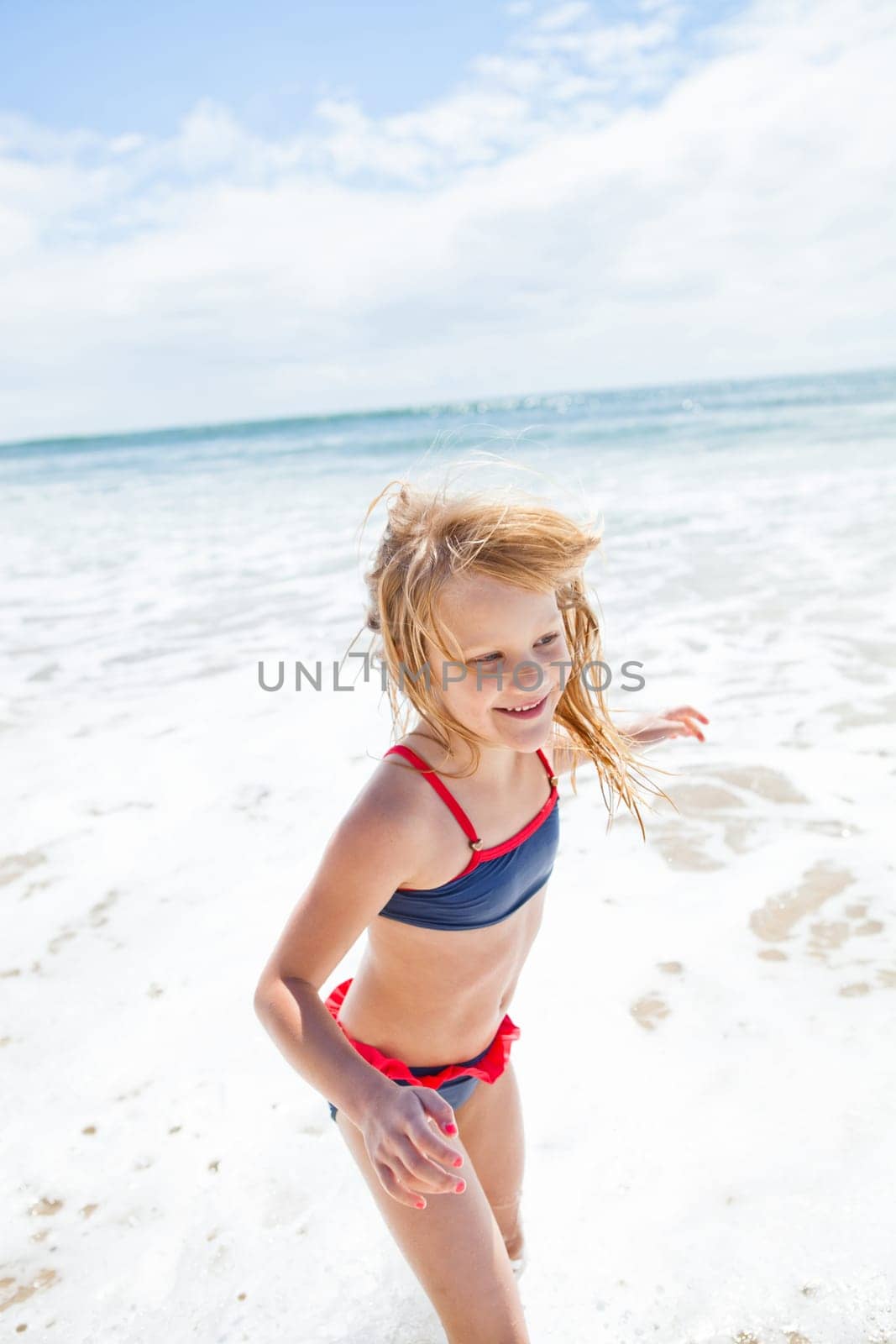 Smiling cute young girl having fun at beach on sunny day