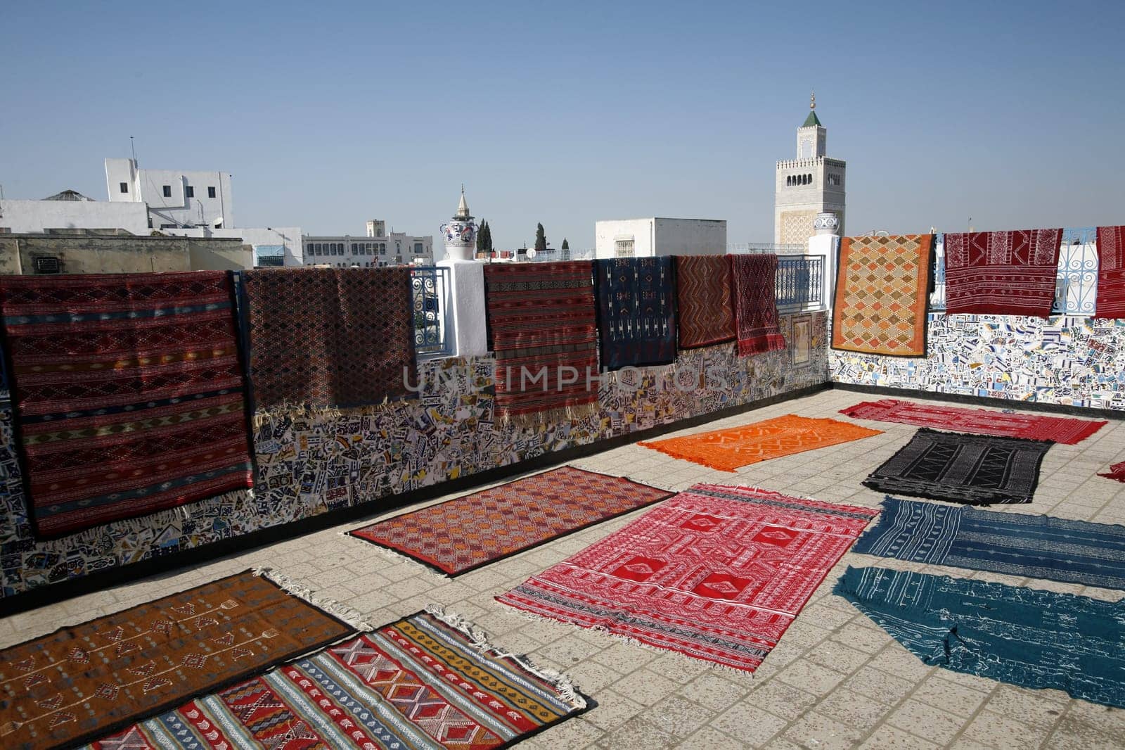 A roof terrace with carpets and the Zaytouna Mosque or Grand Mosque in Souq or Bazzar in the Old Town of Tunis on the Mediterranean Sea in Tunisia in North Africa.