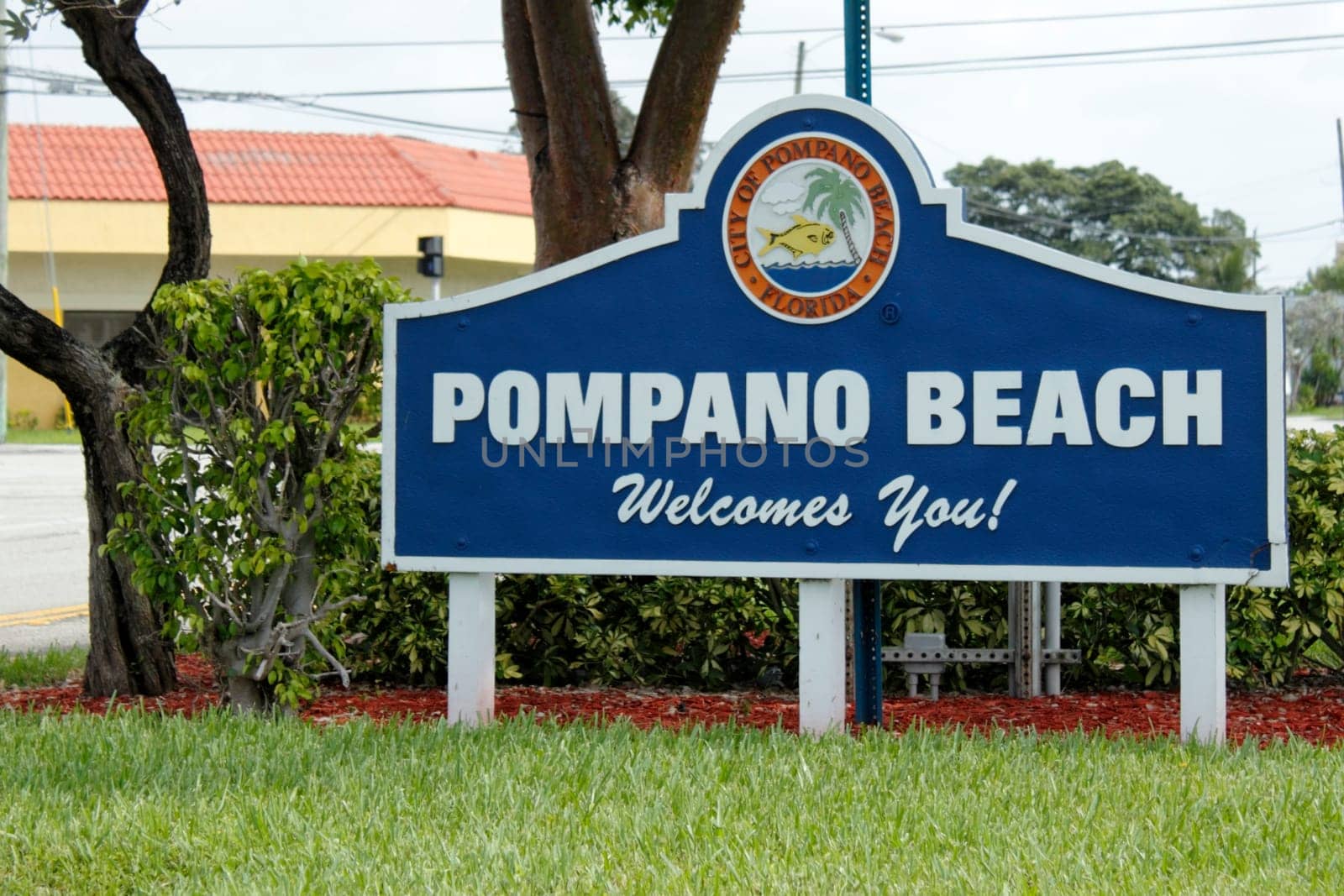 POMPANO BEACH, FLORIDA - JULY 1, 2013: Large white and blue welcome sign at the entrance to the City of Pompano Beach, Florida, population of 102,984 in 2012, that has a colorful tropical graphic.