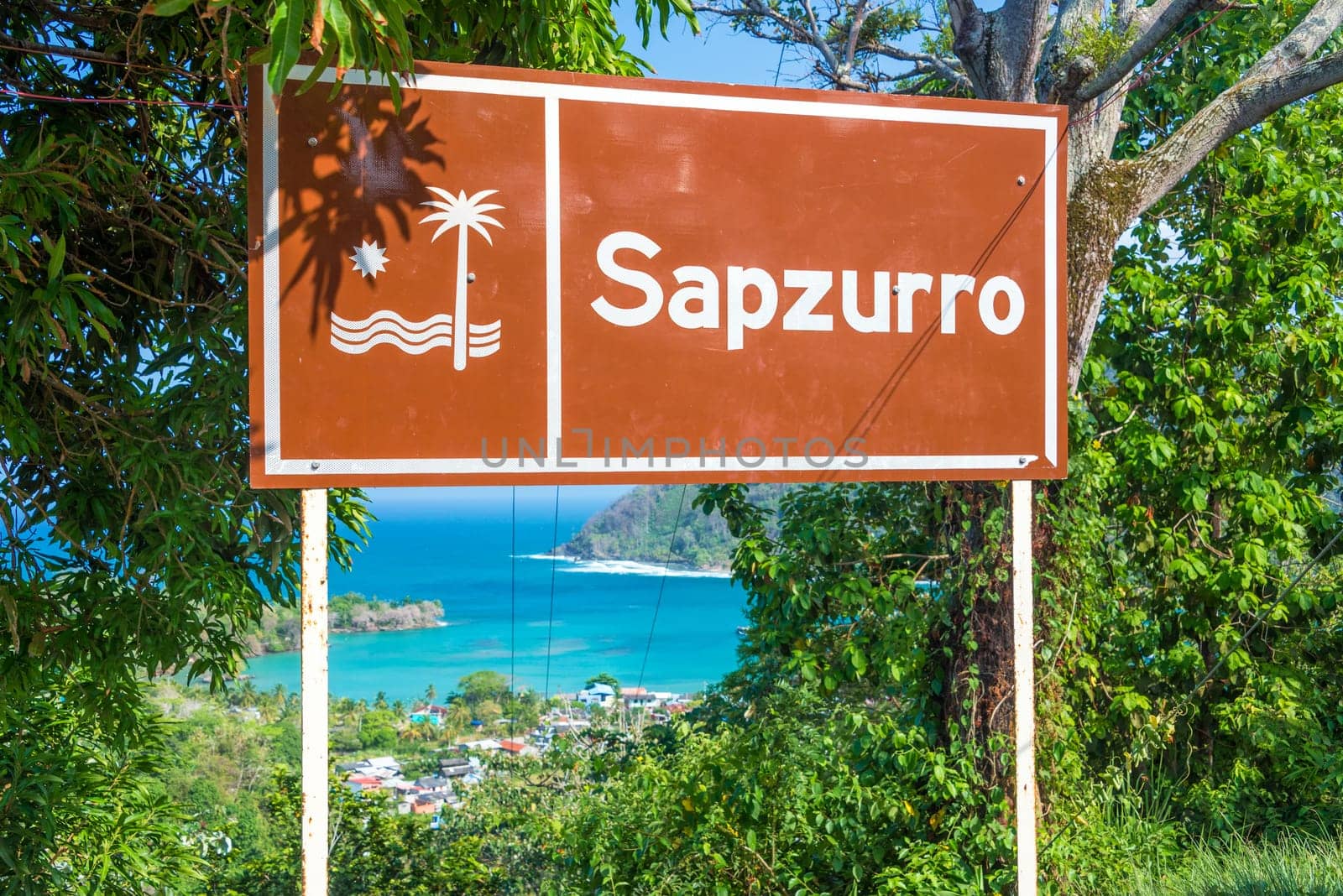 Sign at the entrance to Sapzurro with the town and bay visible below near Capurgana, Colombia