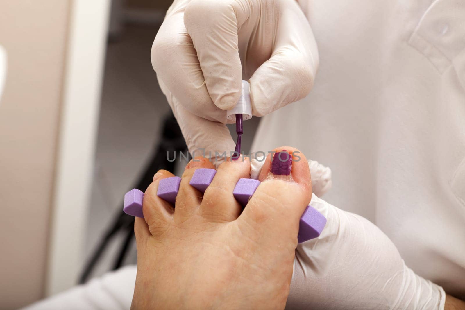 Foot care worker paints a customer's toe nails