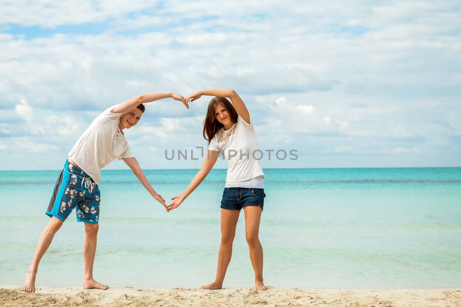 young happy couple in love having fun in summer on the beach