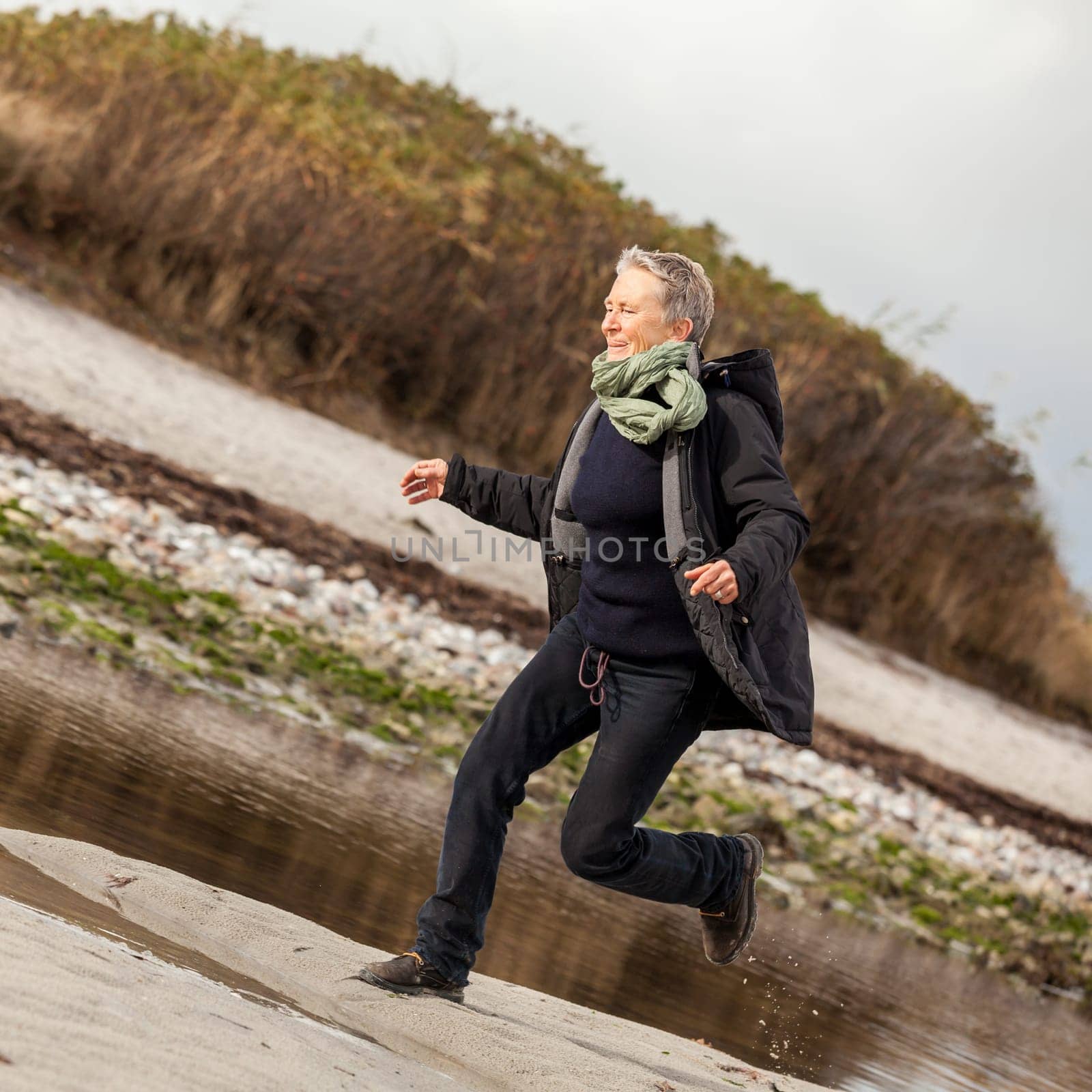 happy active older woman pensioner senior in the open at the sea in autumn