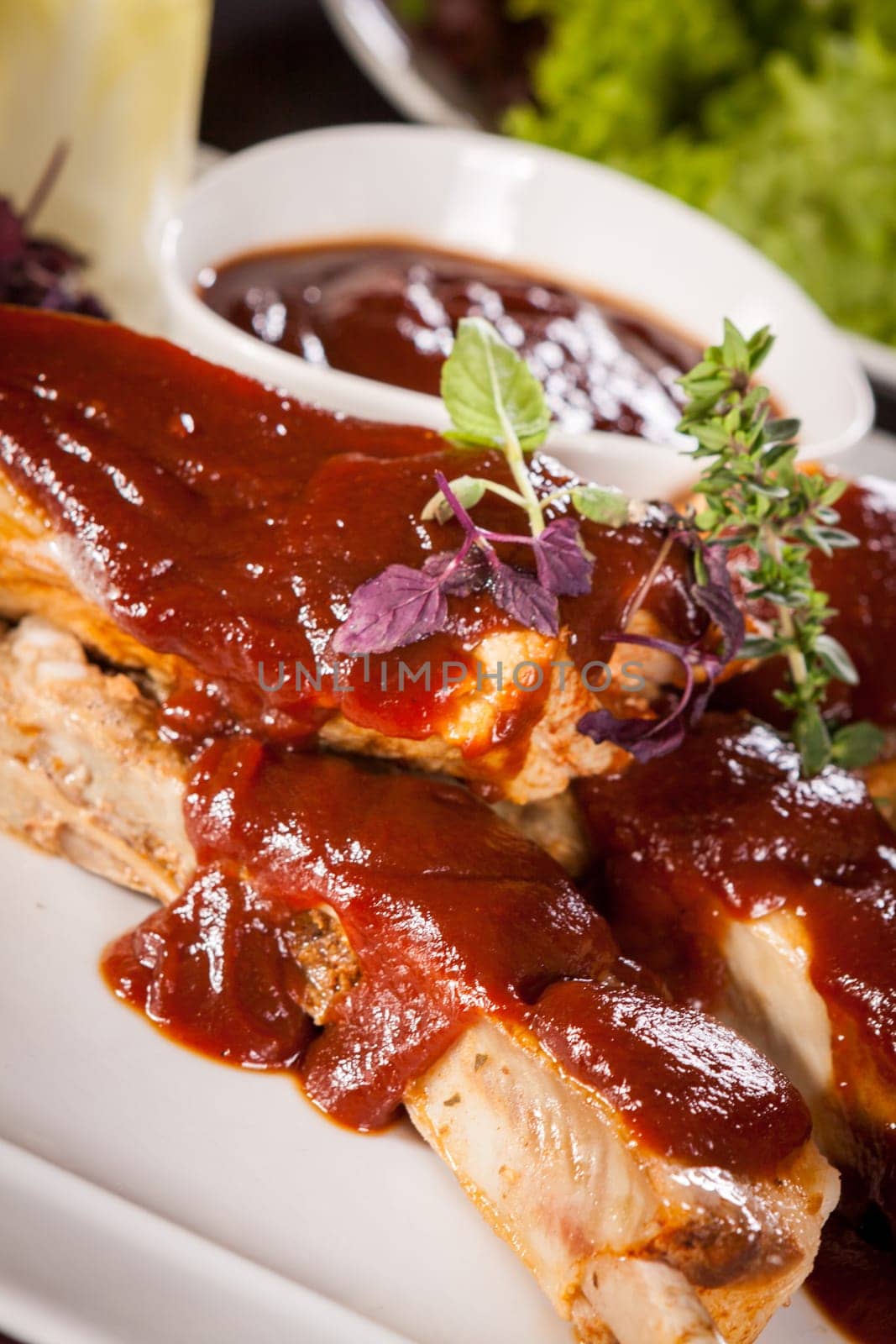 Grilled pork ribs Spareribs with barbecue sauce marinade and herb salad on a plate