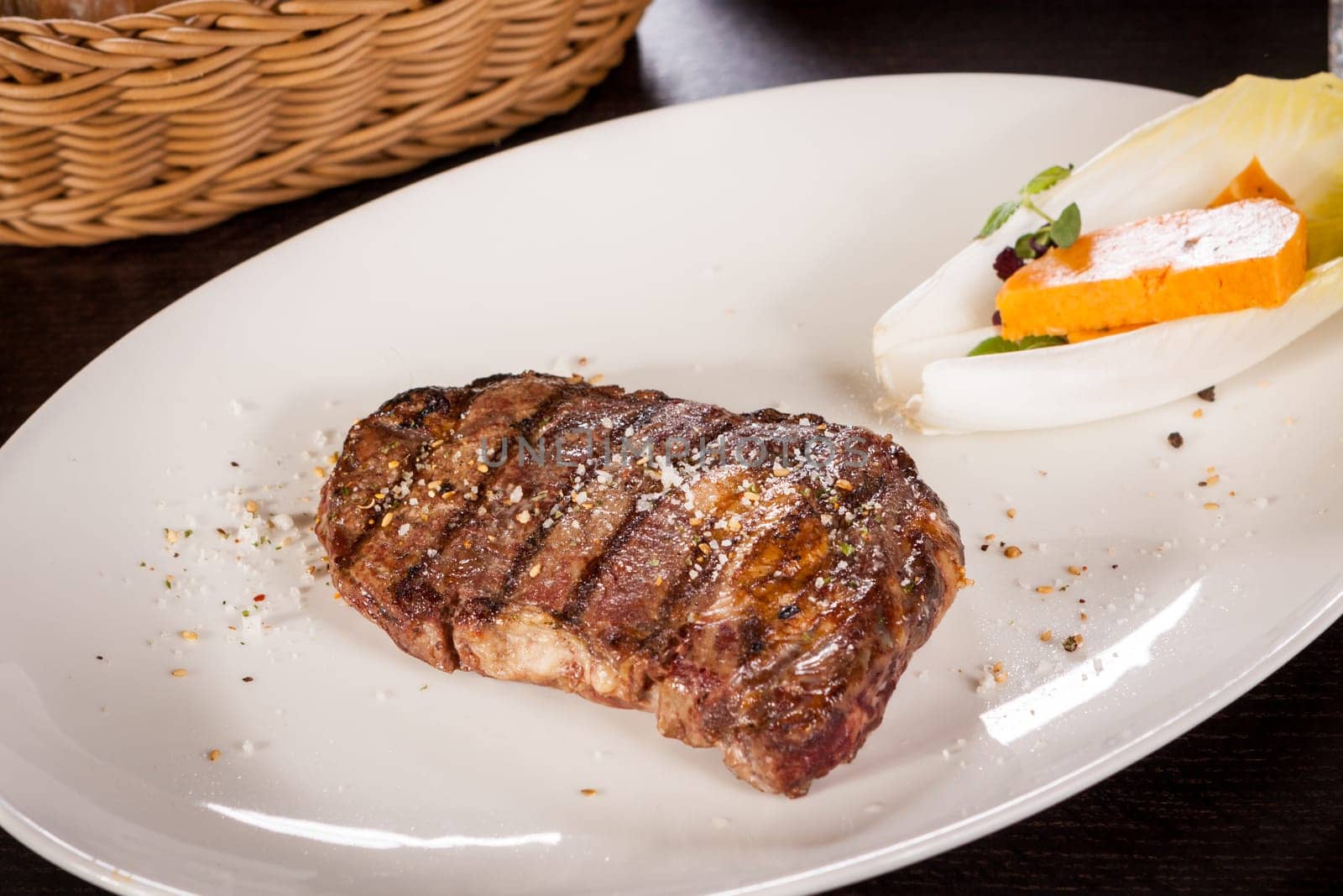 Succulent grilled beef fillet steak with homemade herb butter on a plate isolated against a white background