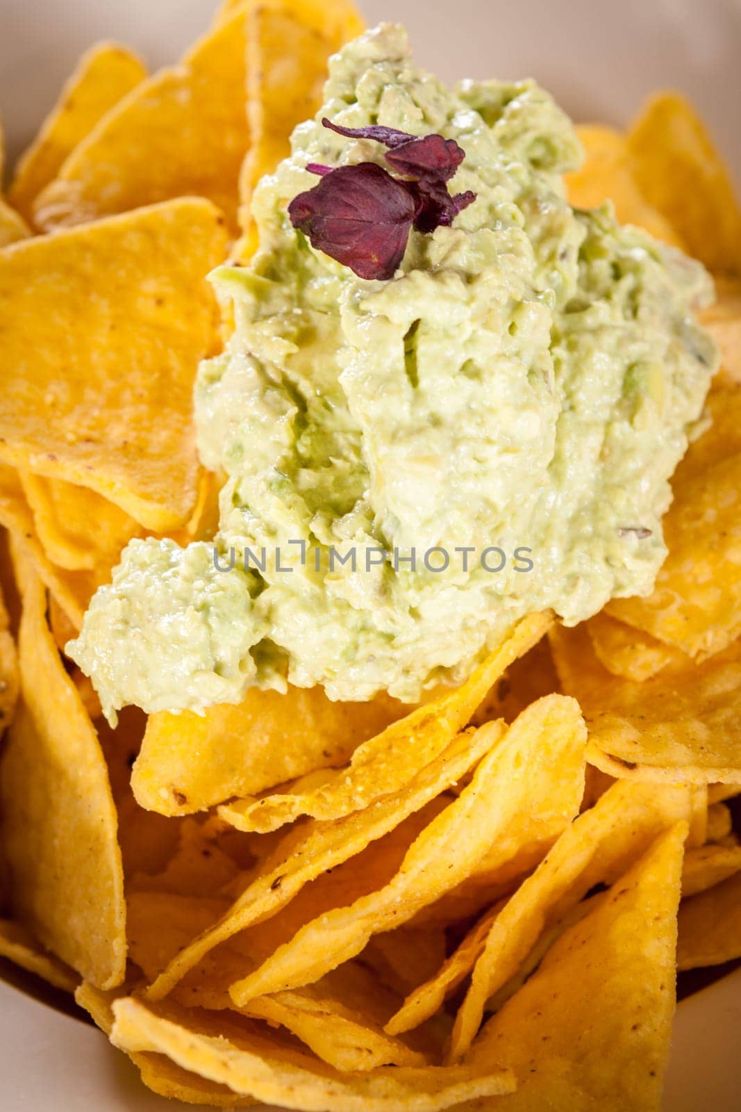 Corn chips nachos with guacamole and salsa dipp in a bowl on a plate