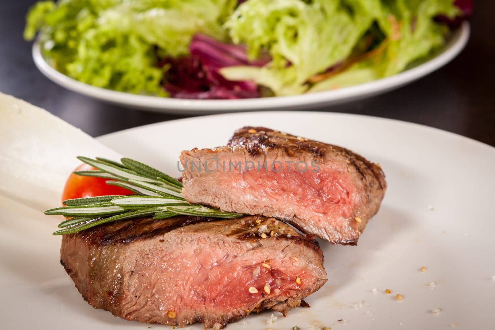 Medium fried beef steak fillet with pepper and rosemary sliced on a plate