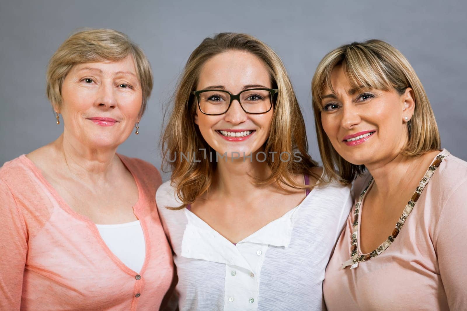 three generations grandmother mother and daughter in portrait against grey background family