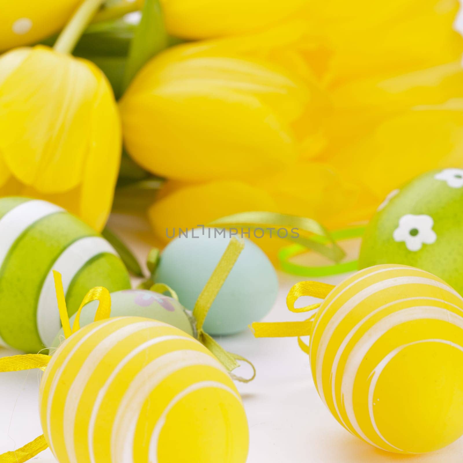 Colourful yellow tulips with green leaves and Easter eggs for Easter Mother's Day Valentine's Day isolated on white background