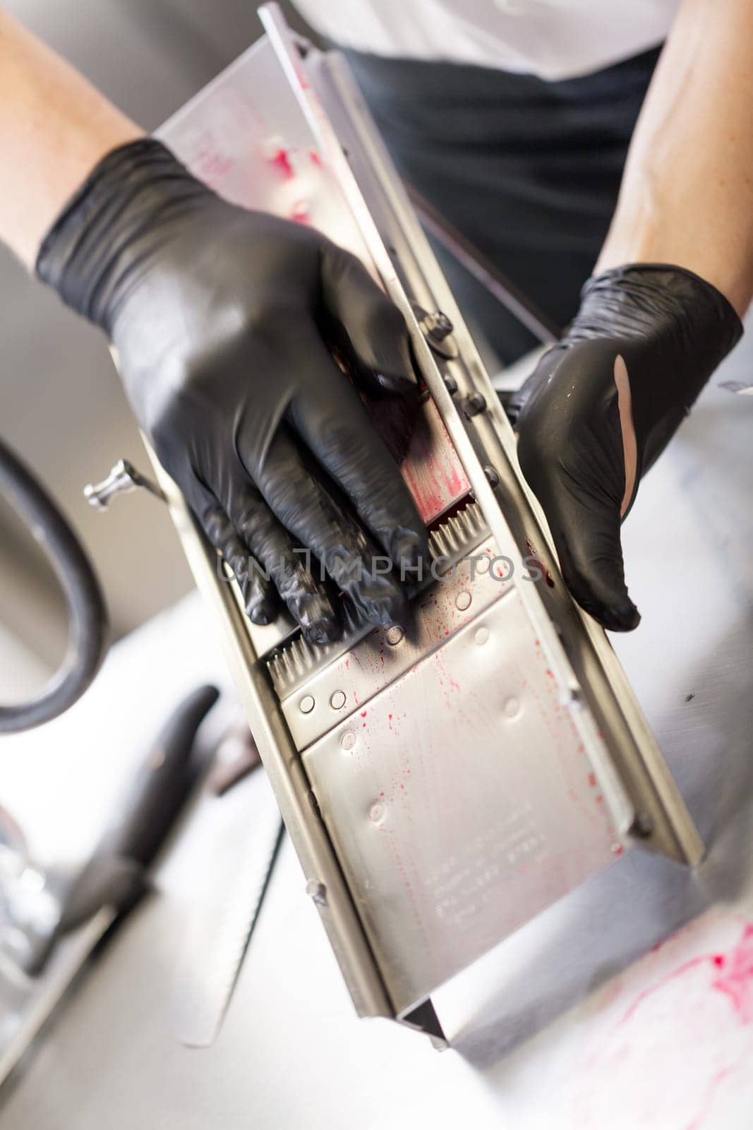 cook rubs fresh red beetroot on rub with gloves to protect against stains in the restaurant kitchen preparation eat