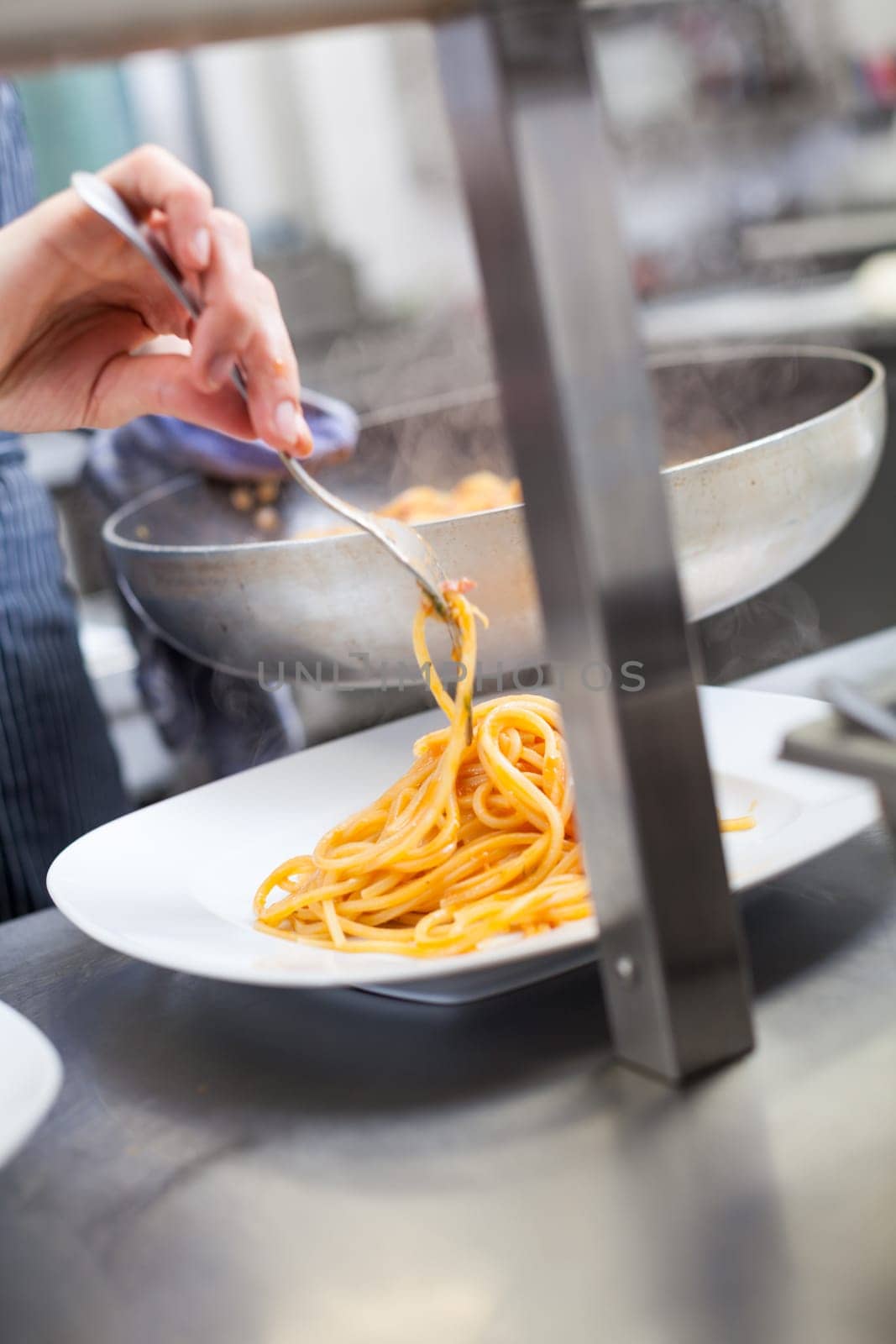 chef prepares fresh pasta spaghetti with shrimp crusts on a plate at the restaurant