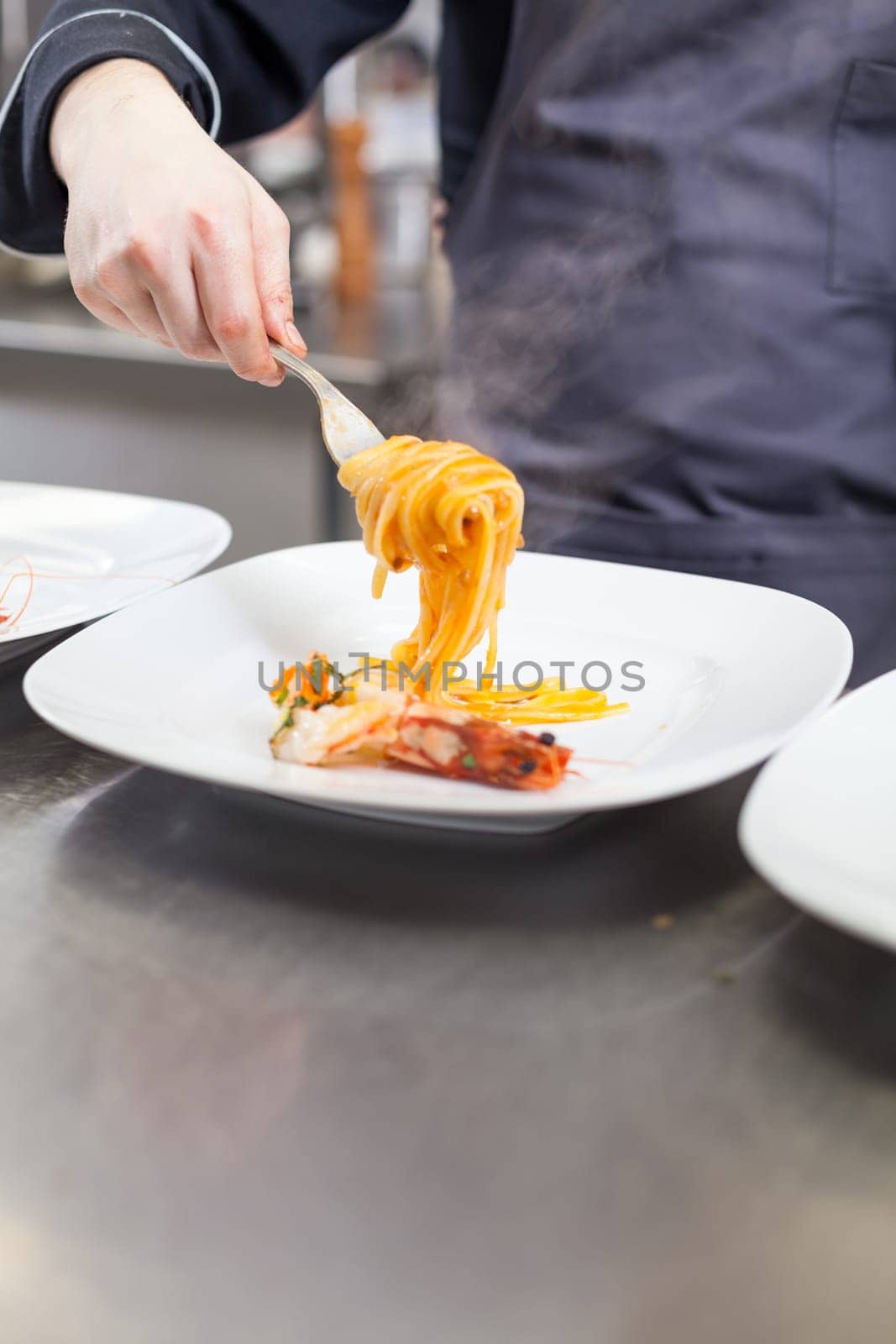 chef prepares fresh pasta spaghetti with shrimp crusts on a plate at the restaurant