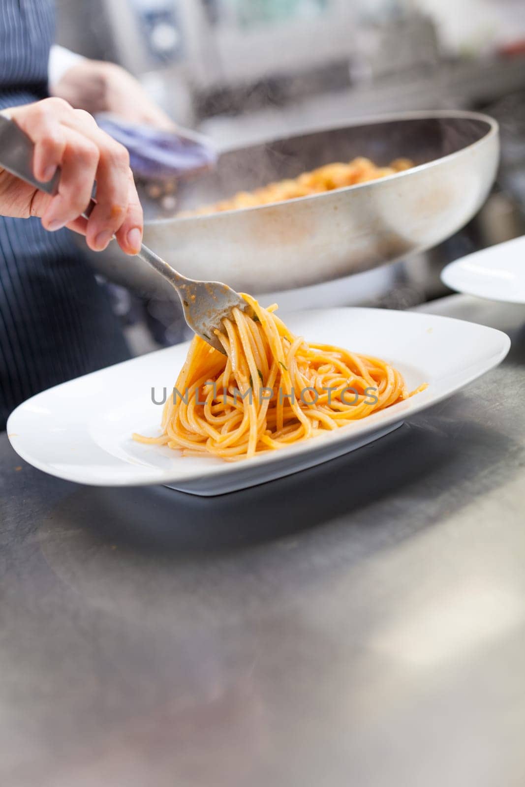 chef prepares fresh pasta spaghetti with shrimp crusts on a plate at the restaurant