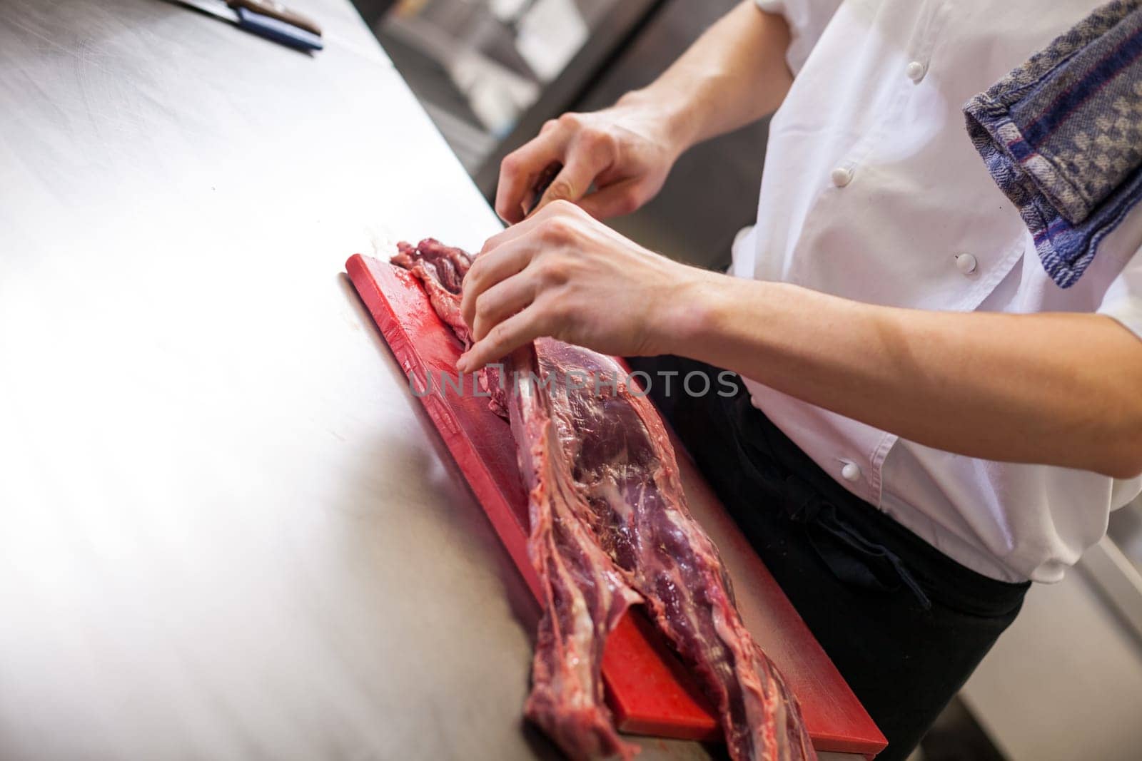 chef cuts fresh red meat in the restaurant kitchen gastronomy food work cooking