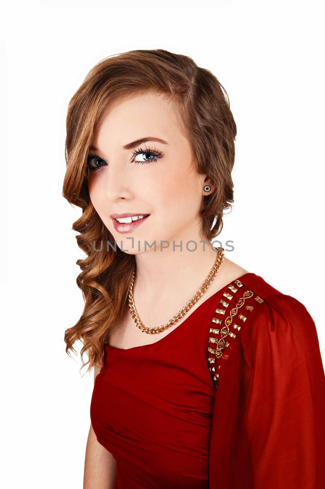 A beautiful young woman in a red dress and with long curly hair standing.for white background, smiling into the camera..