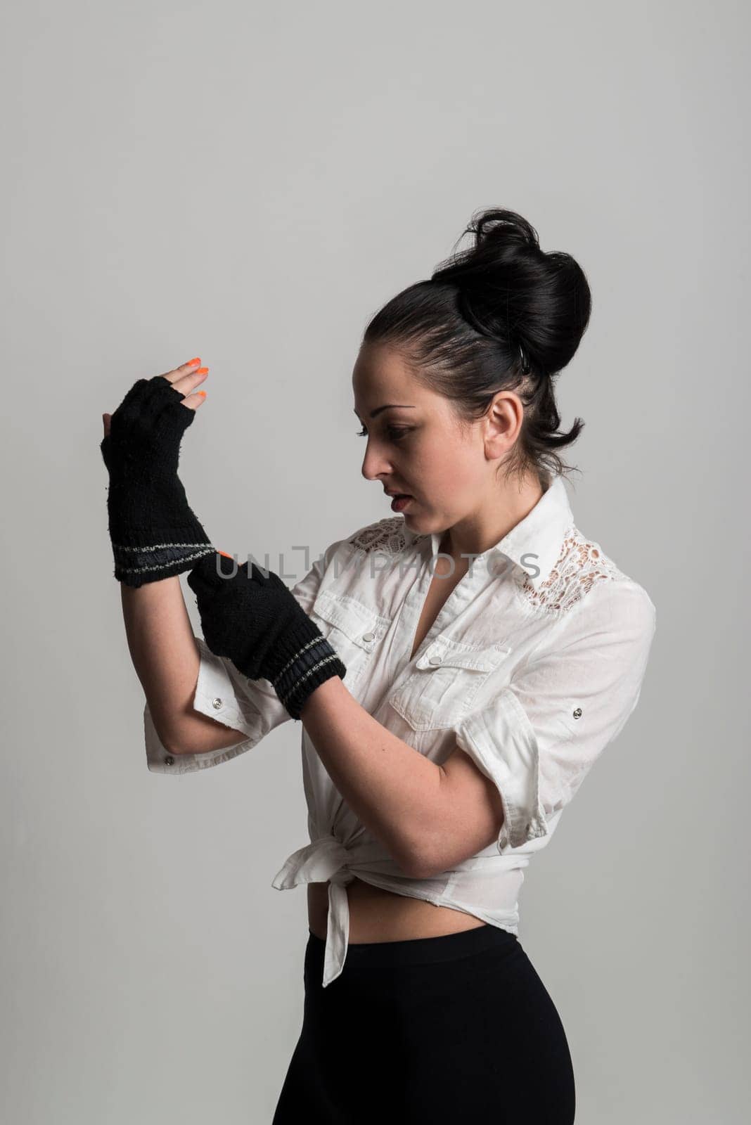Fashion portrait of beautiful caucasian female model wearing white shirt and wearing fingerless gloves