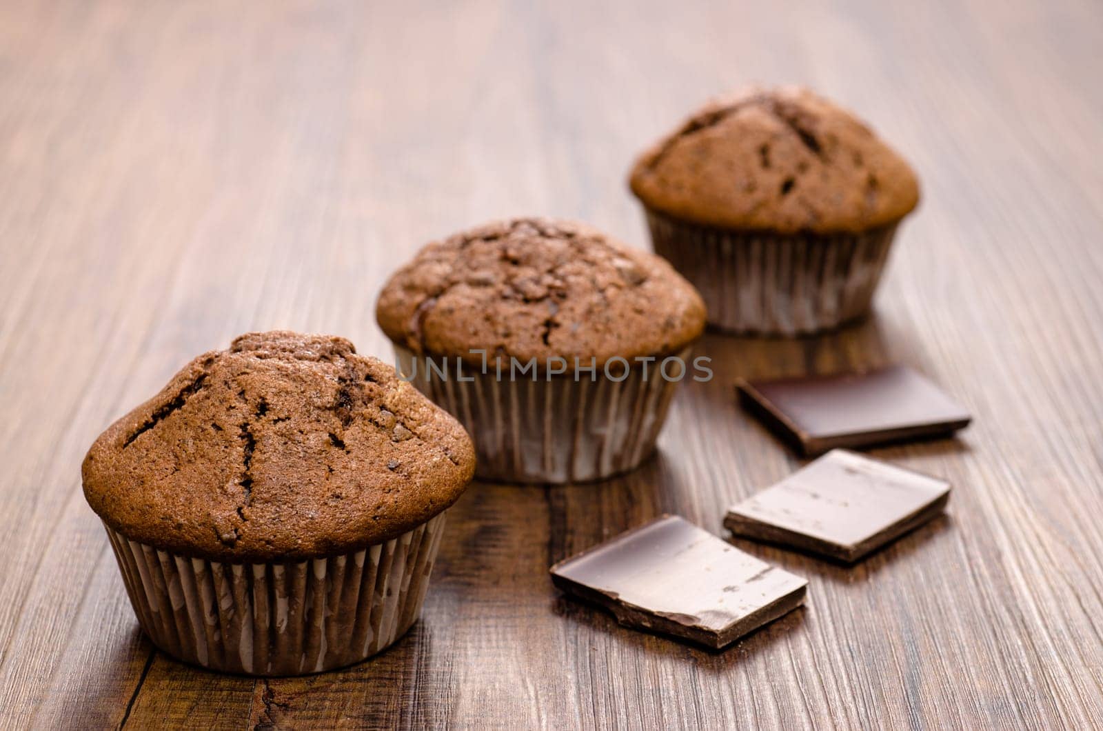 Muffins with chocolate in the backlight on a wooden table