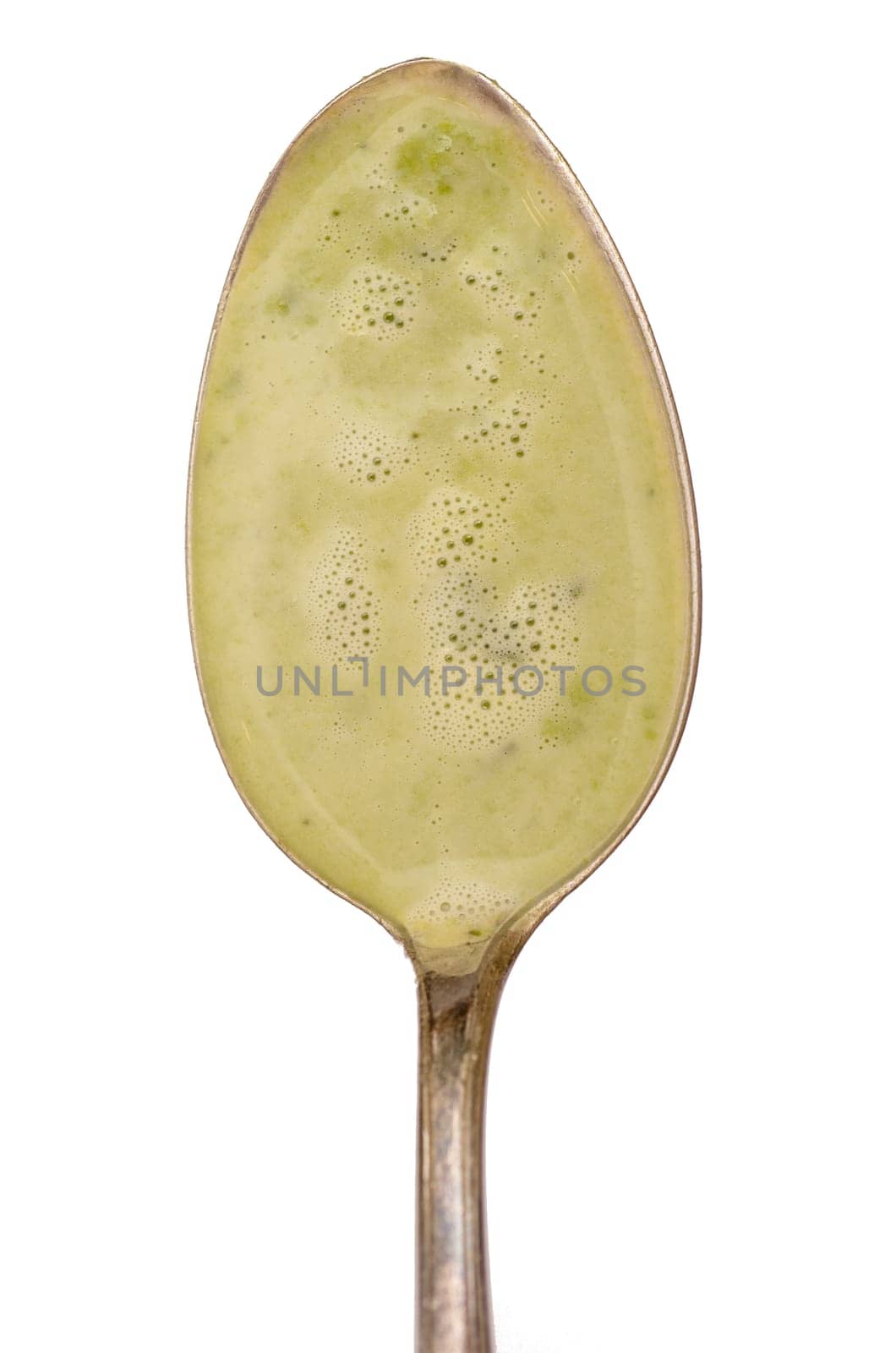 Spoon with green soup of peas in portrait format