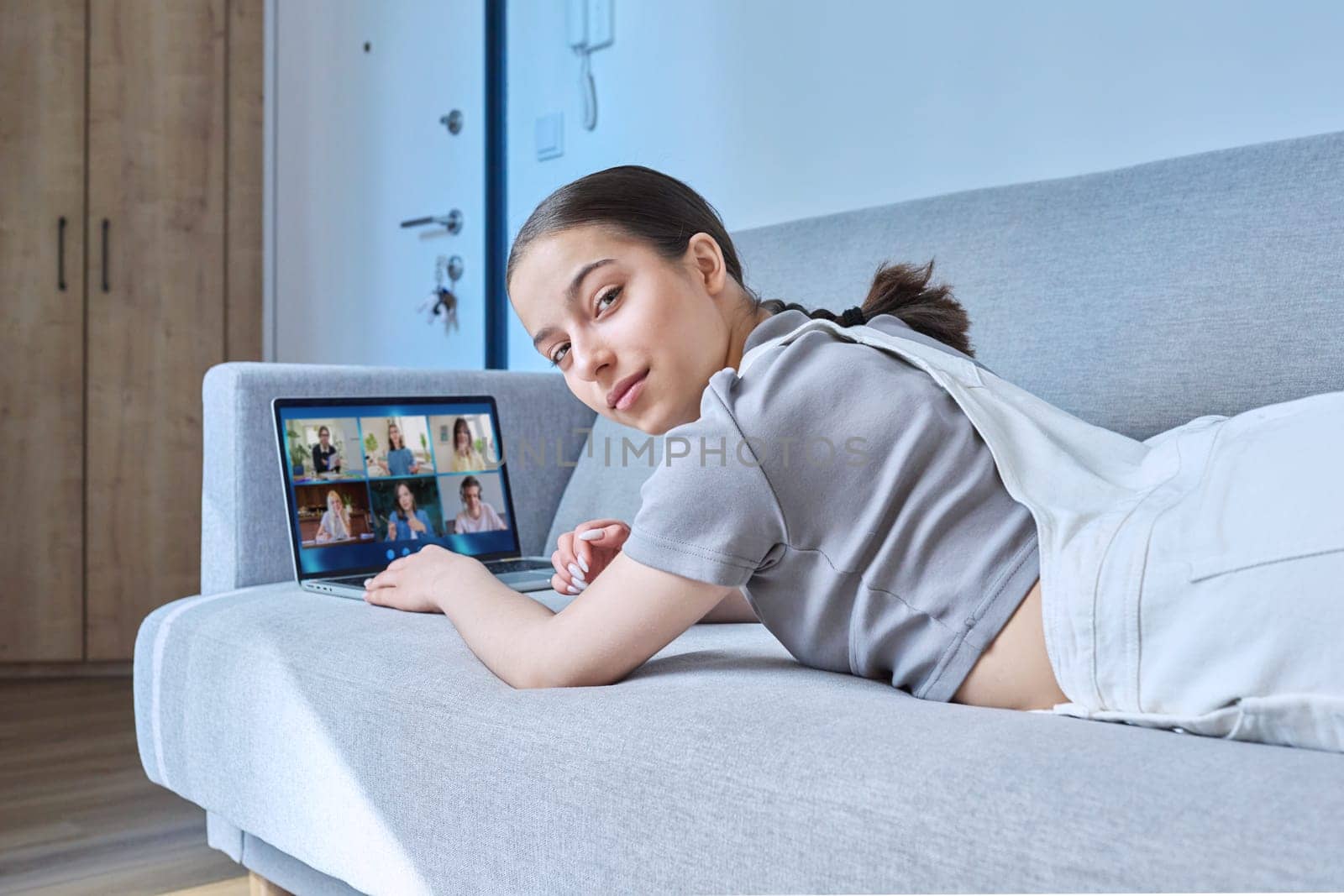 Video conference, laptop screen with group of students and teacher, teen girl looking at camera studying remotely at home. Online lesson distance learning course. E-education technology high school