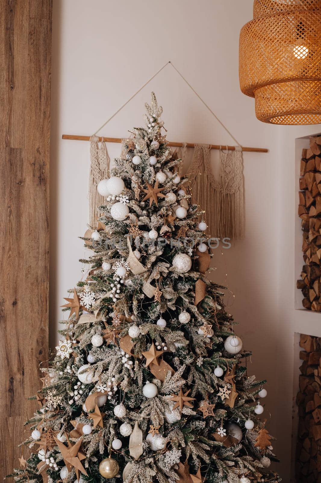 Christmas morning interior with christmas tree decorated deer and big window. Beige cozy loft with lights. Vintage interior. Gold balls on the Christmas tree. Xmas gifts in craft paper. New Year.