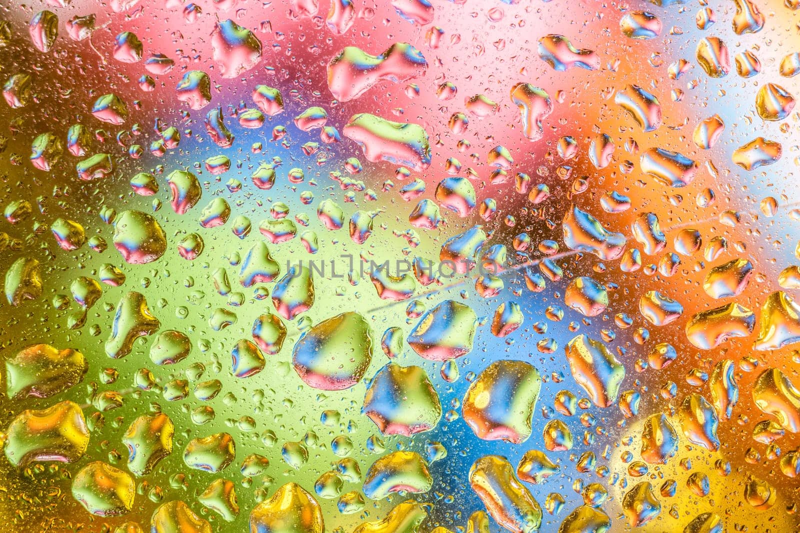 A bright colorful background image of water droplets on a glass surface