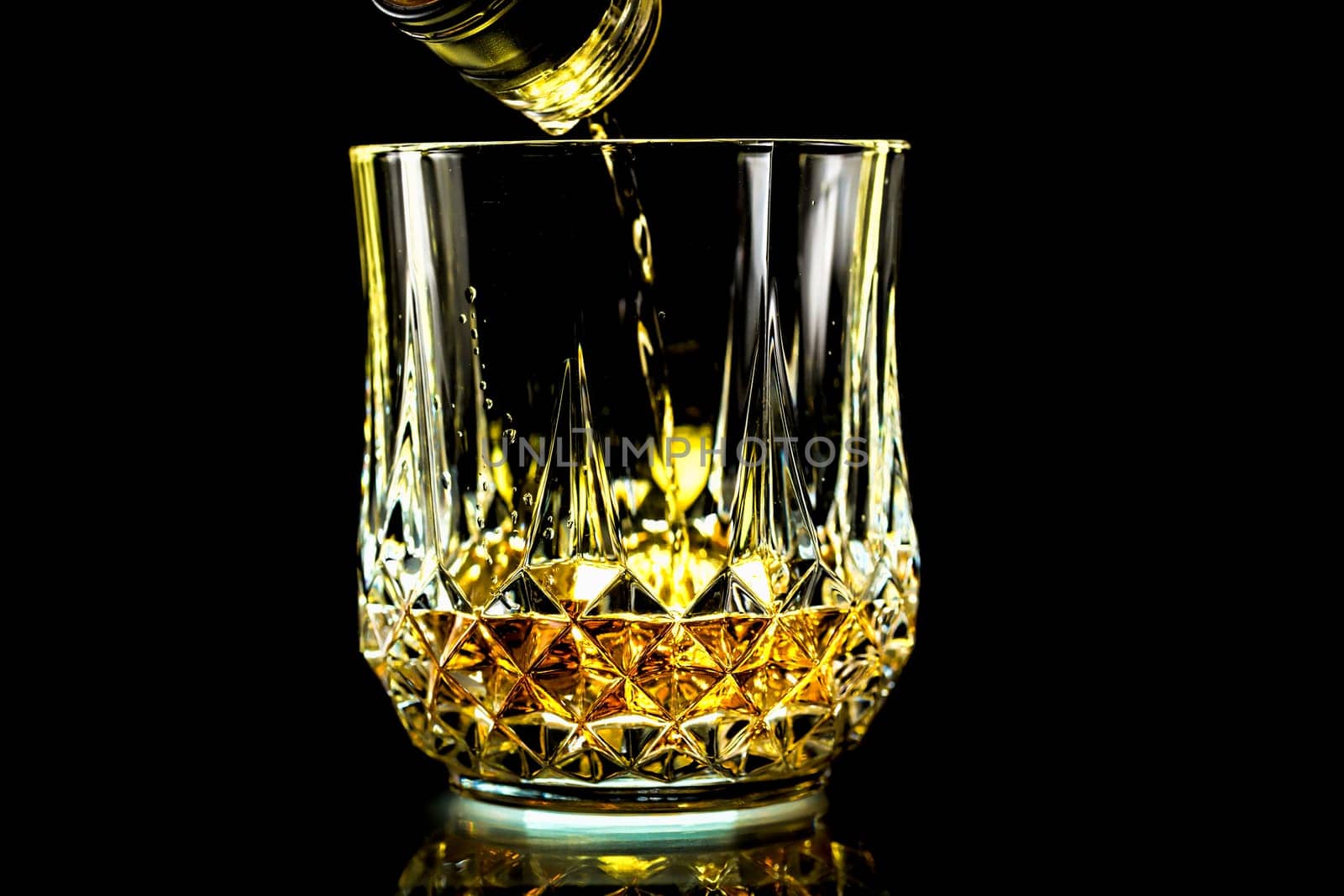 Pouring a glass of crisp golden whiskey from a bottle