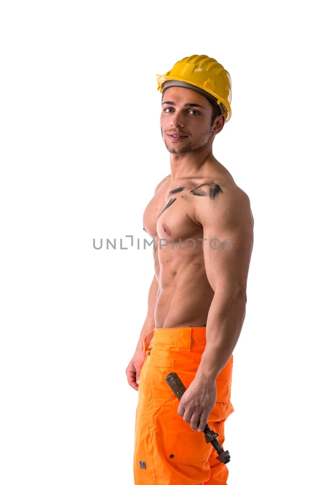Profile view of muscular young construction worker shirtless, with yellow hardhat