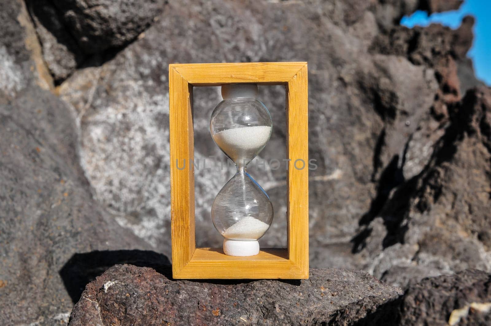 Time Concept White Sand Hourglass on the Volcanic Rocks