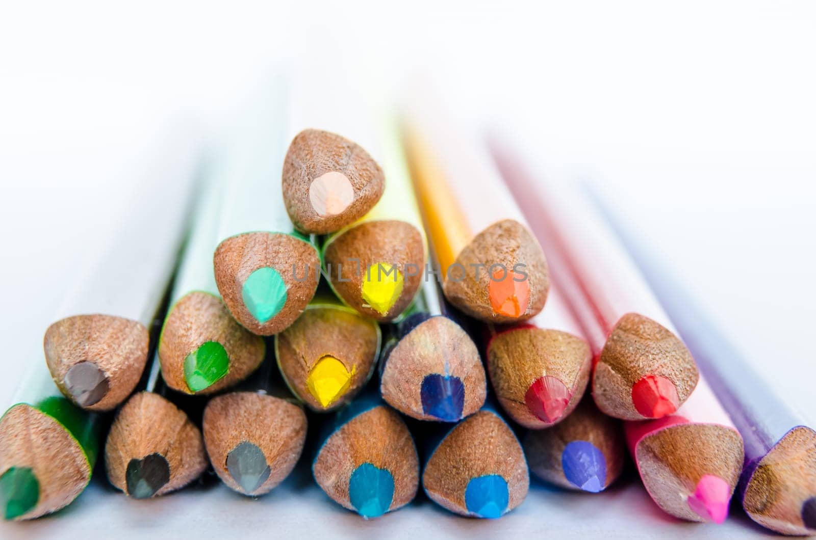 Close up detail of colorful pencils in a small stack on white background